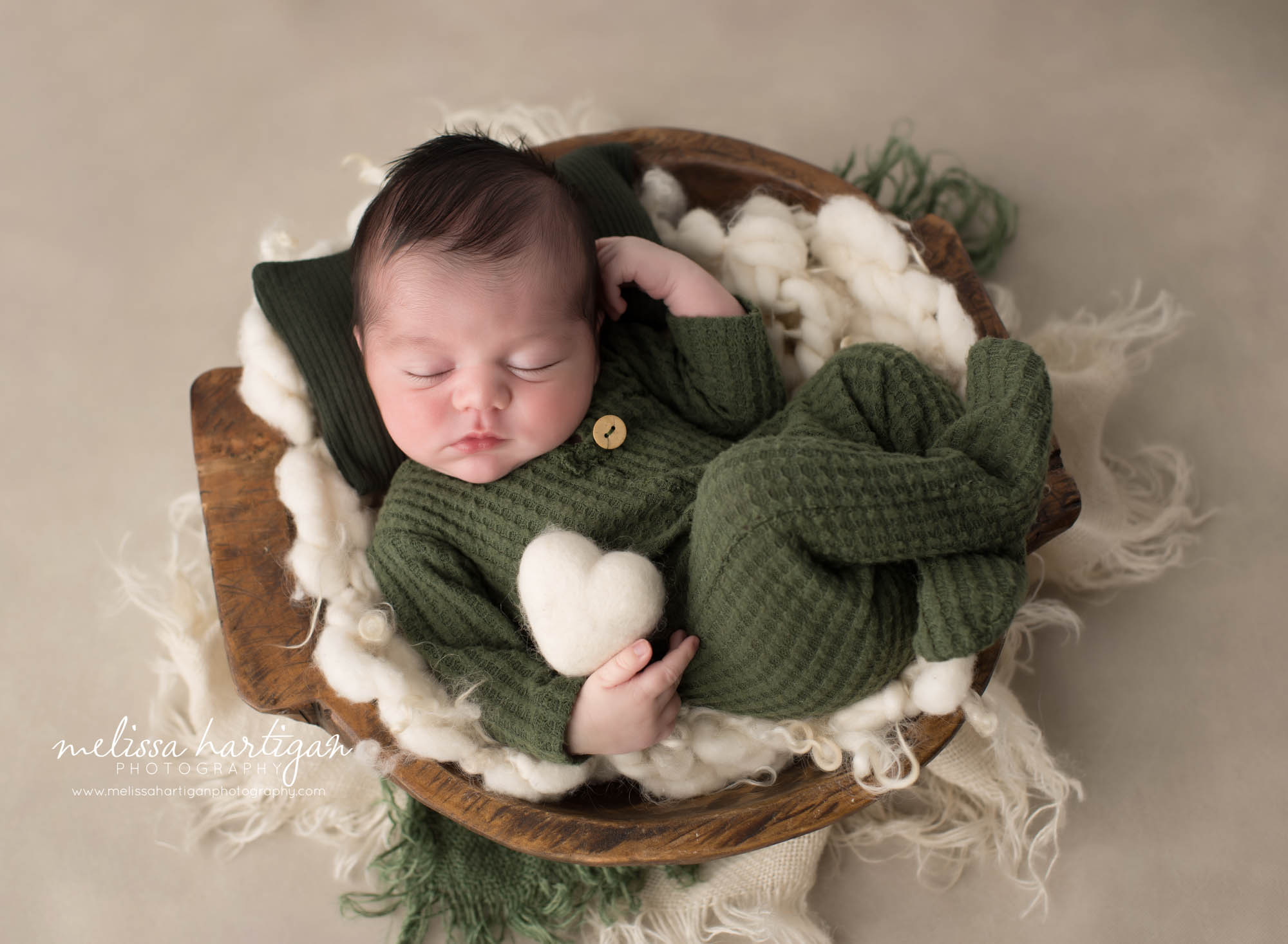 Newborn baby boy posed in bowl wearing green waffled footed newborn outfit Newborn Photography Ellington CT