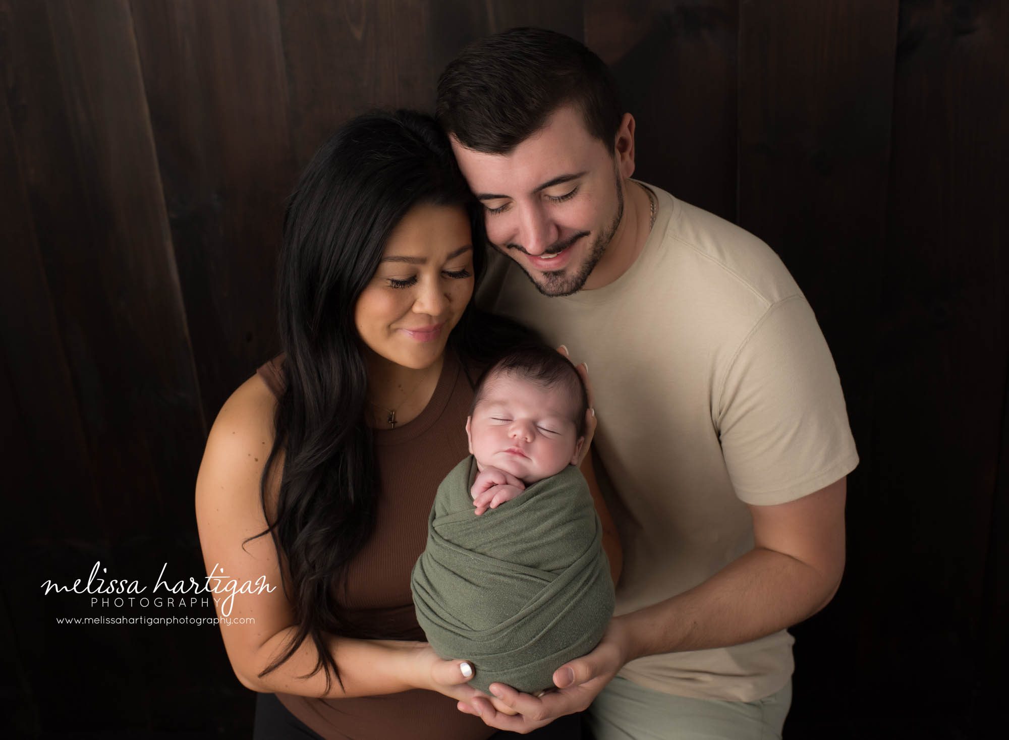 Mom and dad holding swaddled newborn son in family pose