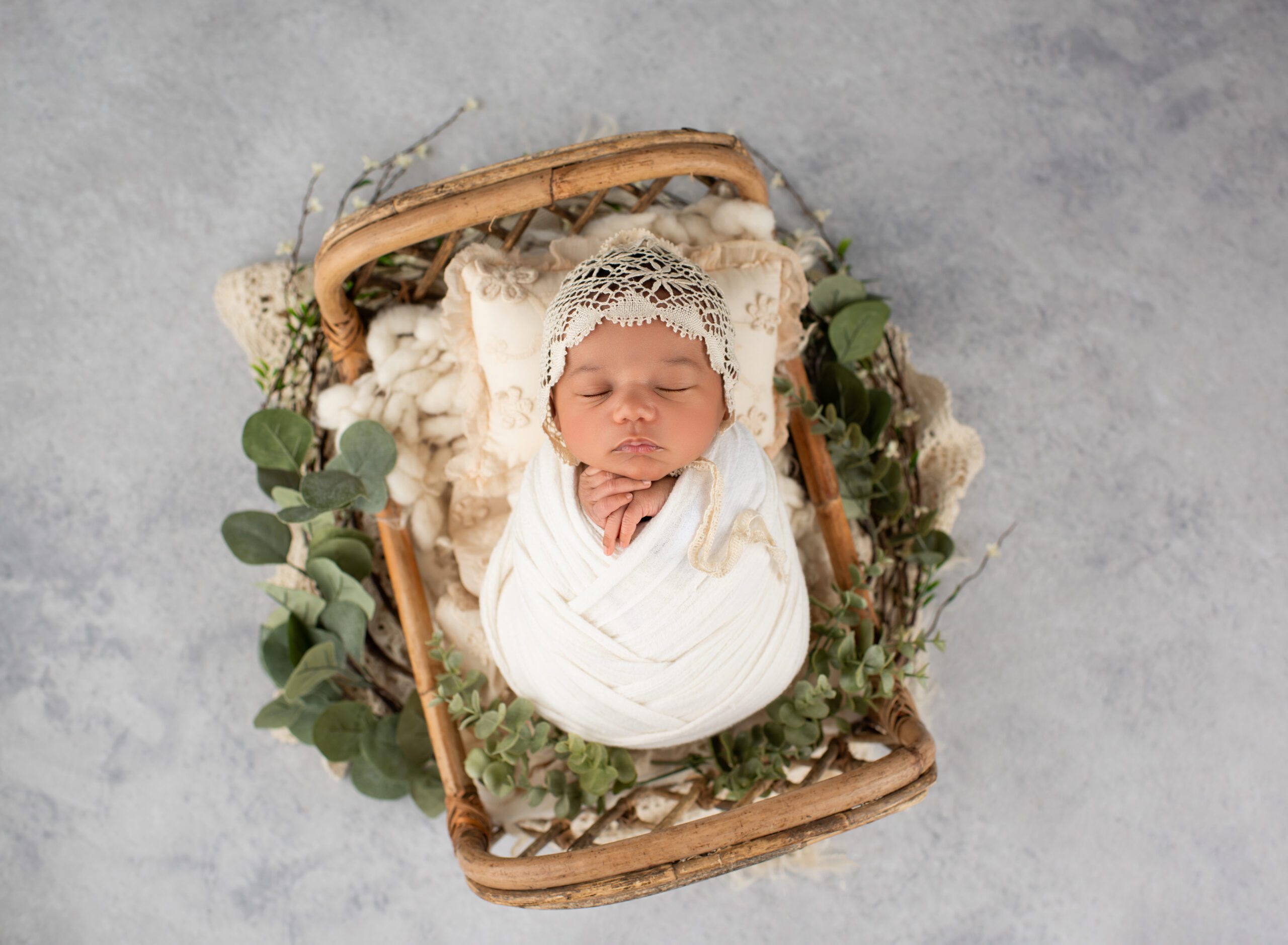 Newborn baby girl posed in basket wearing lace bonnet Newborn Photography Simsbury CT