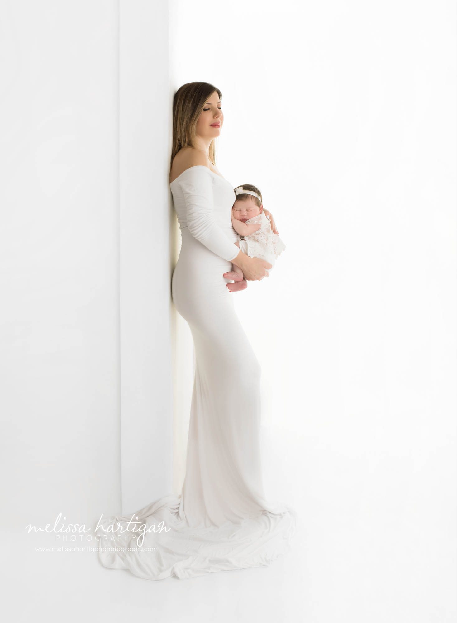 Mom wearing white long form fitted dress holding newborn baby girl in white setup Newborn Photography Farmington CT