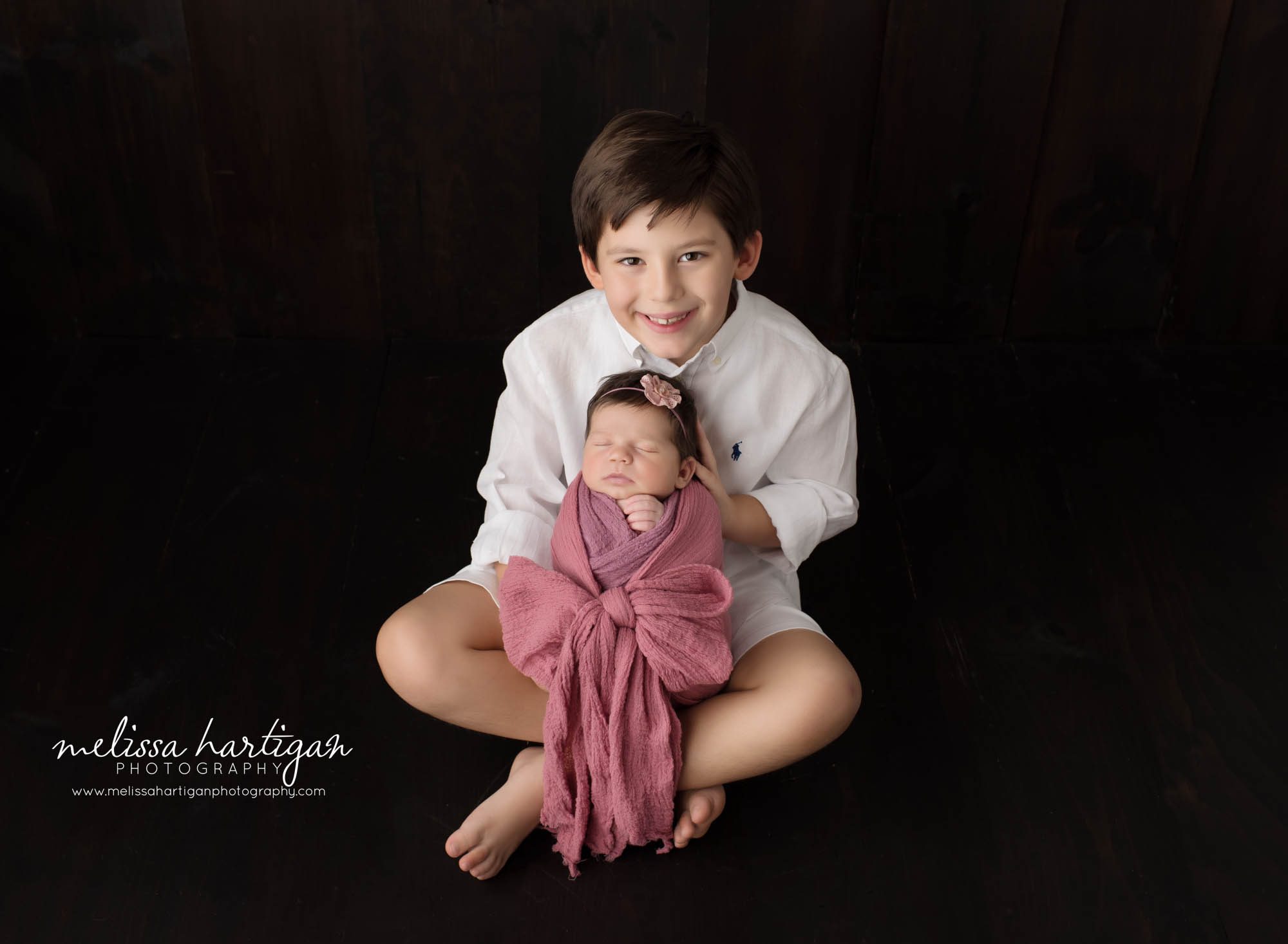 Big brother holding newborn baby sister