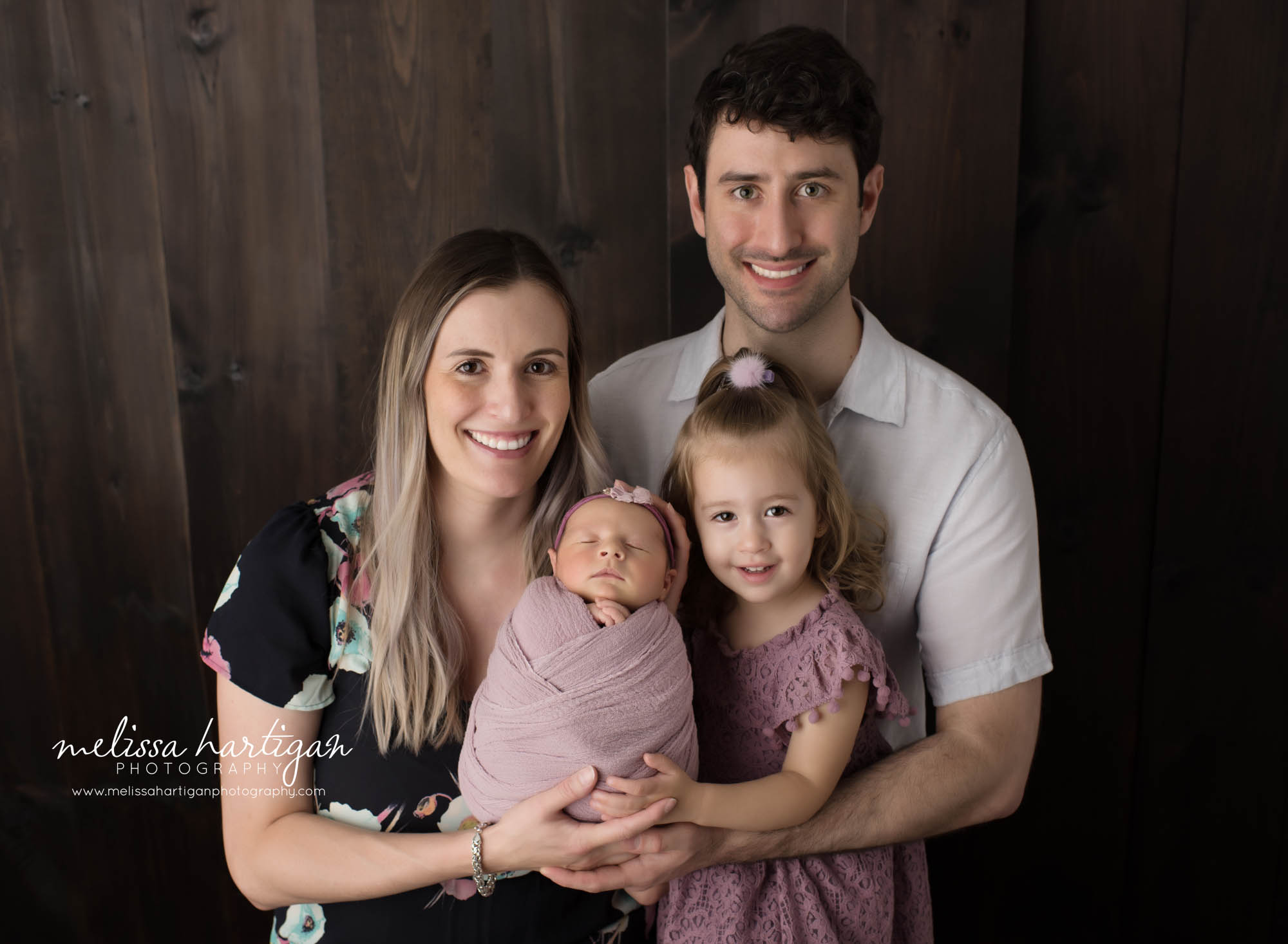 family of four posed together mom dad and 2 daughters Newborn Photography Weston CT