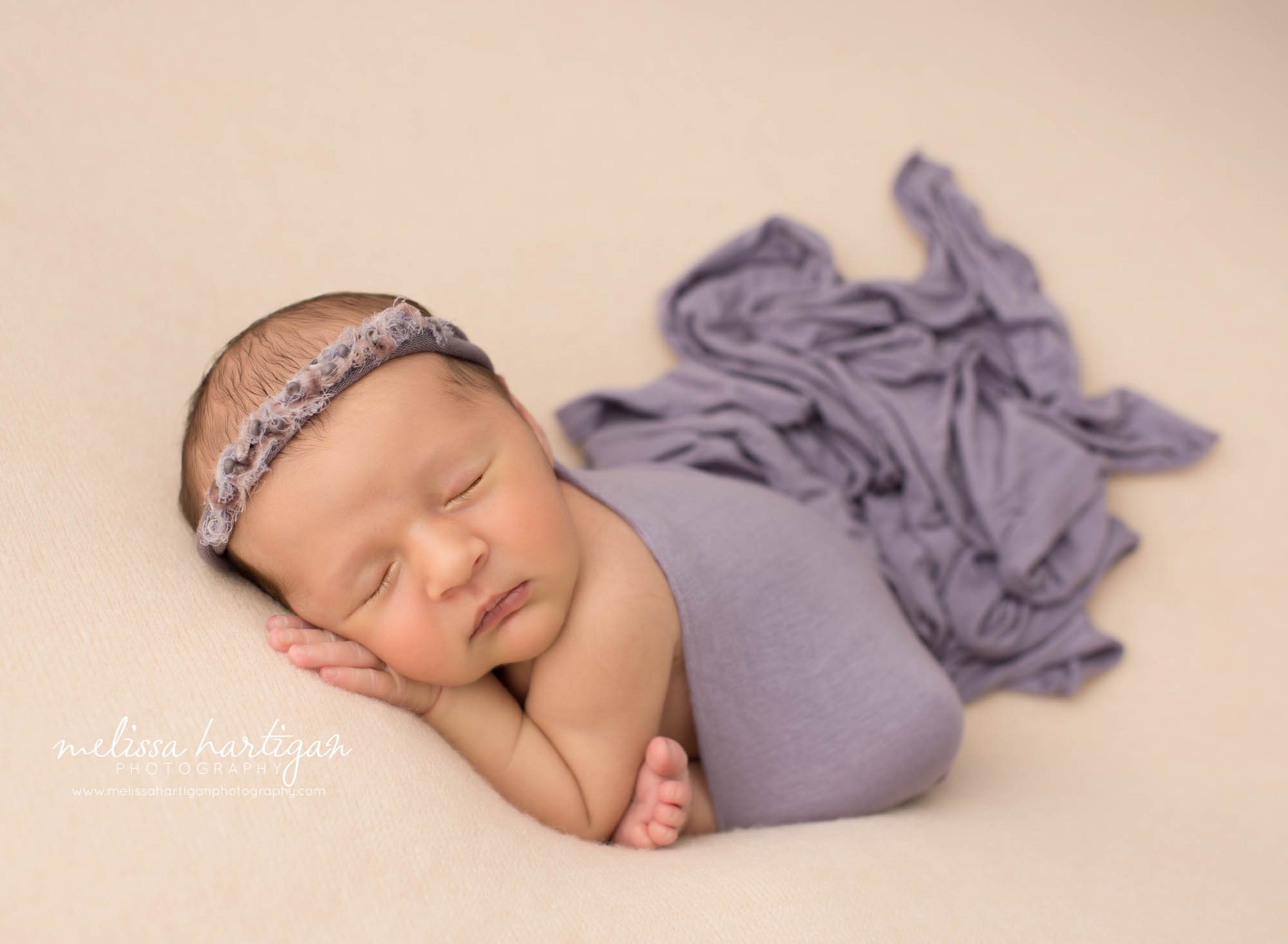 newborn baby girl posed on tummy wearing purple headband Newborn Photography Weston CT