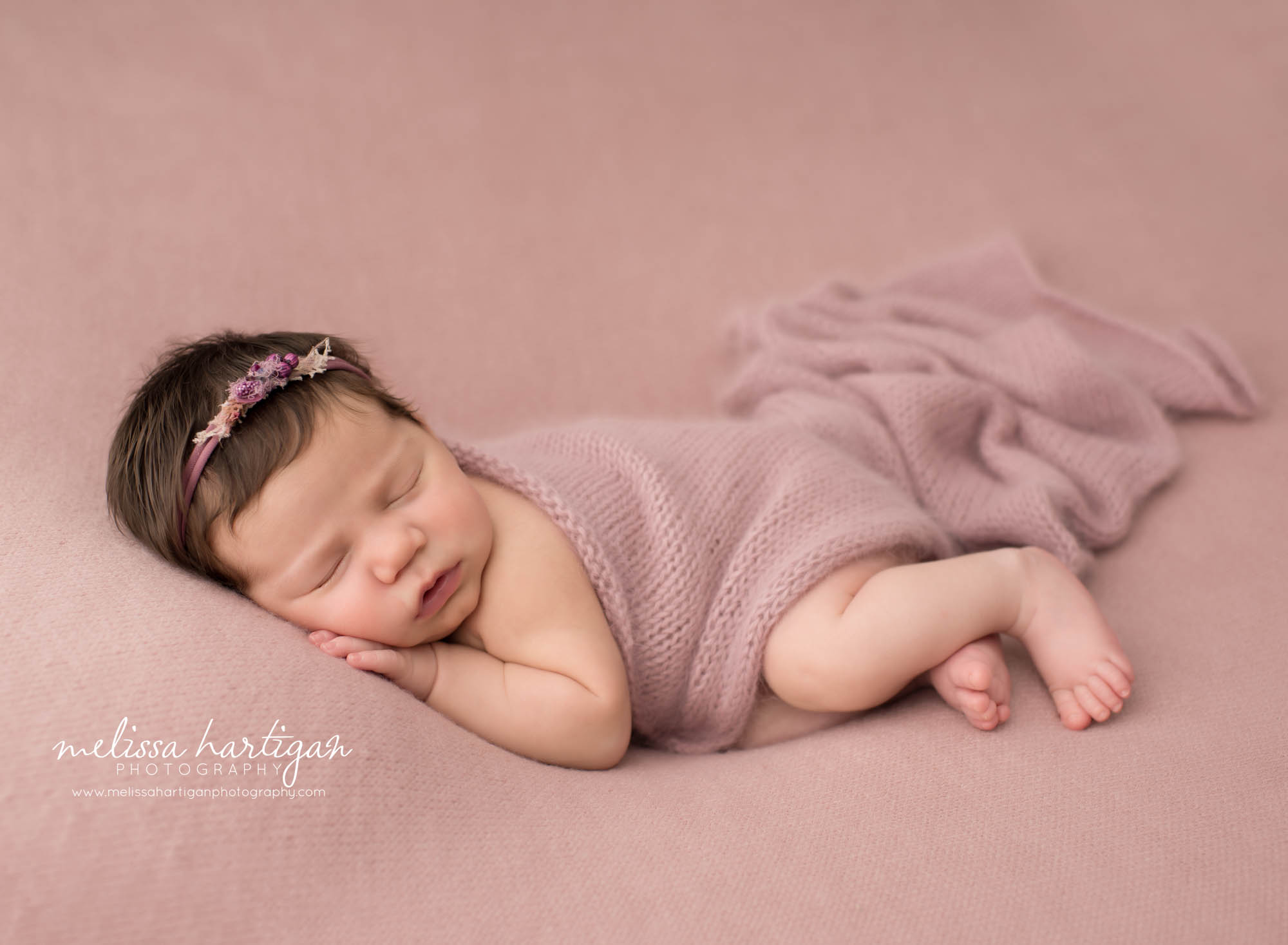 Newborn baby girl posed on side with pink knit layer draped over her Newborn Photography Farmington CT