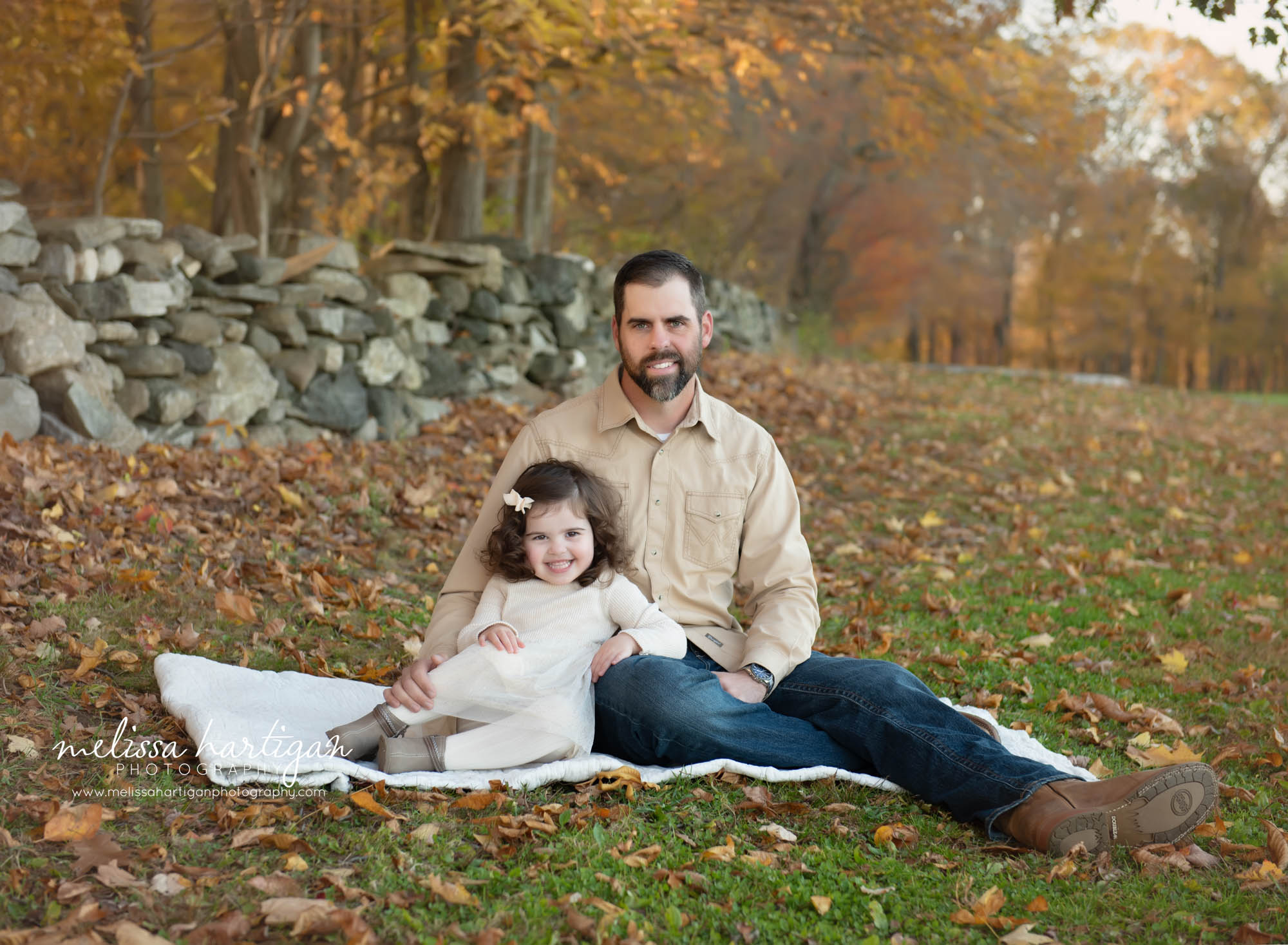 Dad sitting with daughter on blanket on grass
