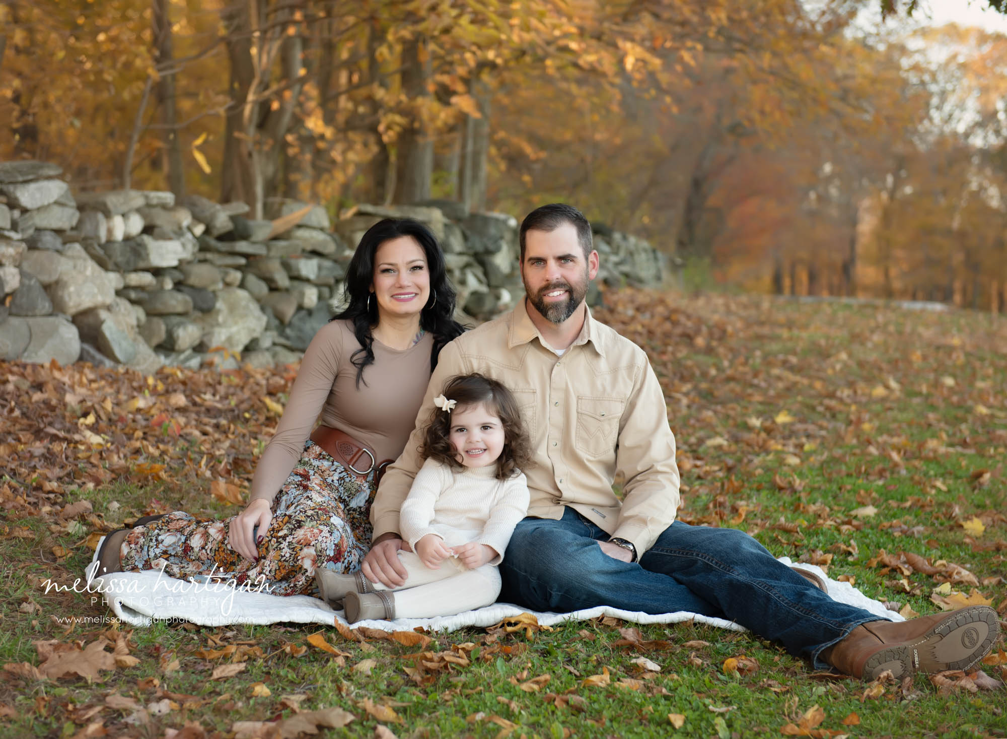 mom dad and daughter sitting on blanket for family pose together CT Family Photography