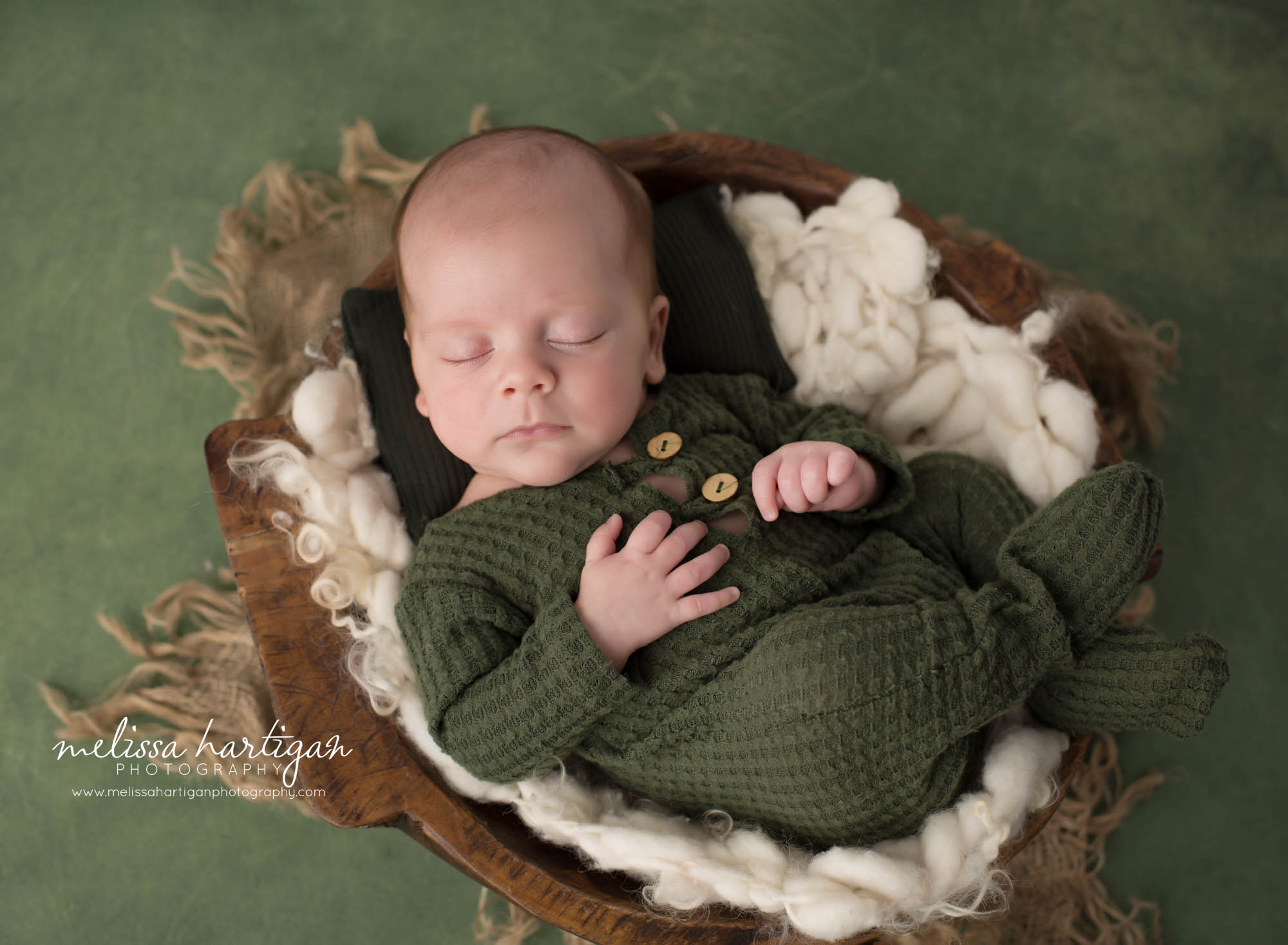 Newborn baby boy posed in wooden bowl wearing green footed sleeper Willington CT Newborn Photography