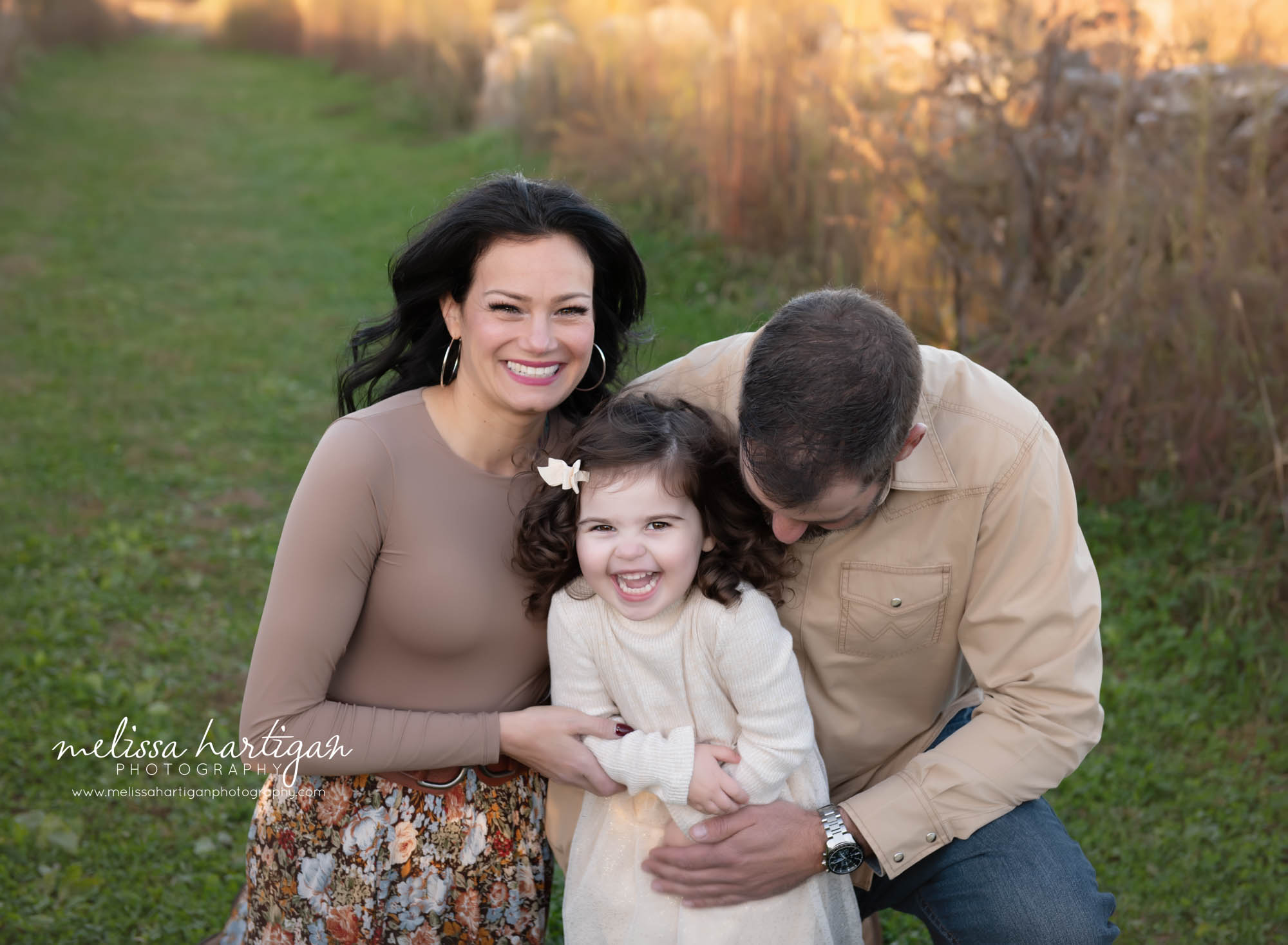 Dad tickling daughter in family photo