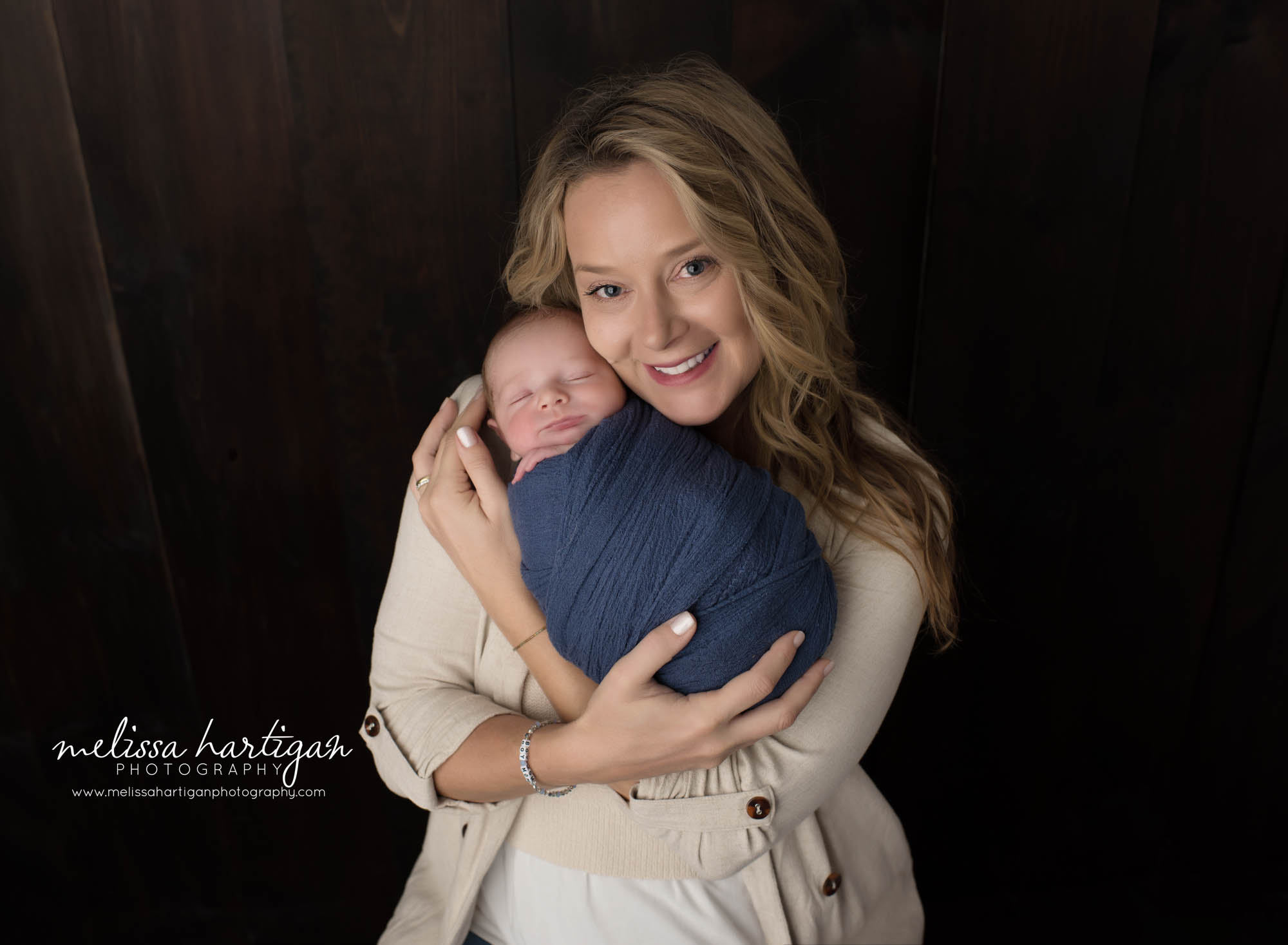 Mom smiling holding swaddled newborn son Newborn Photography Portland CT