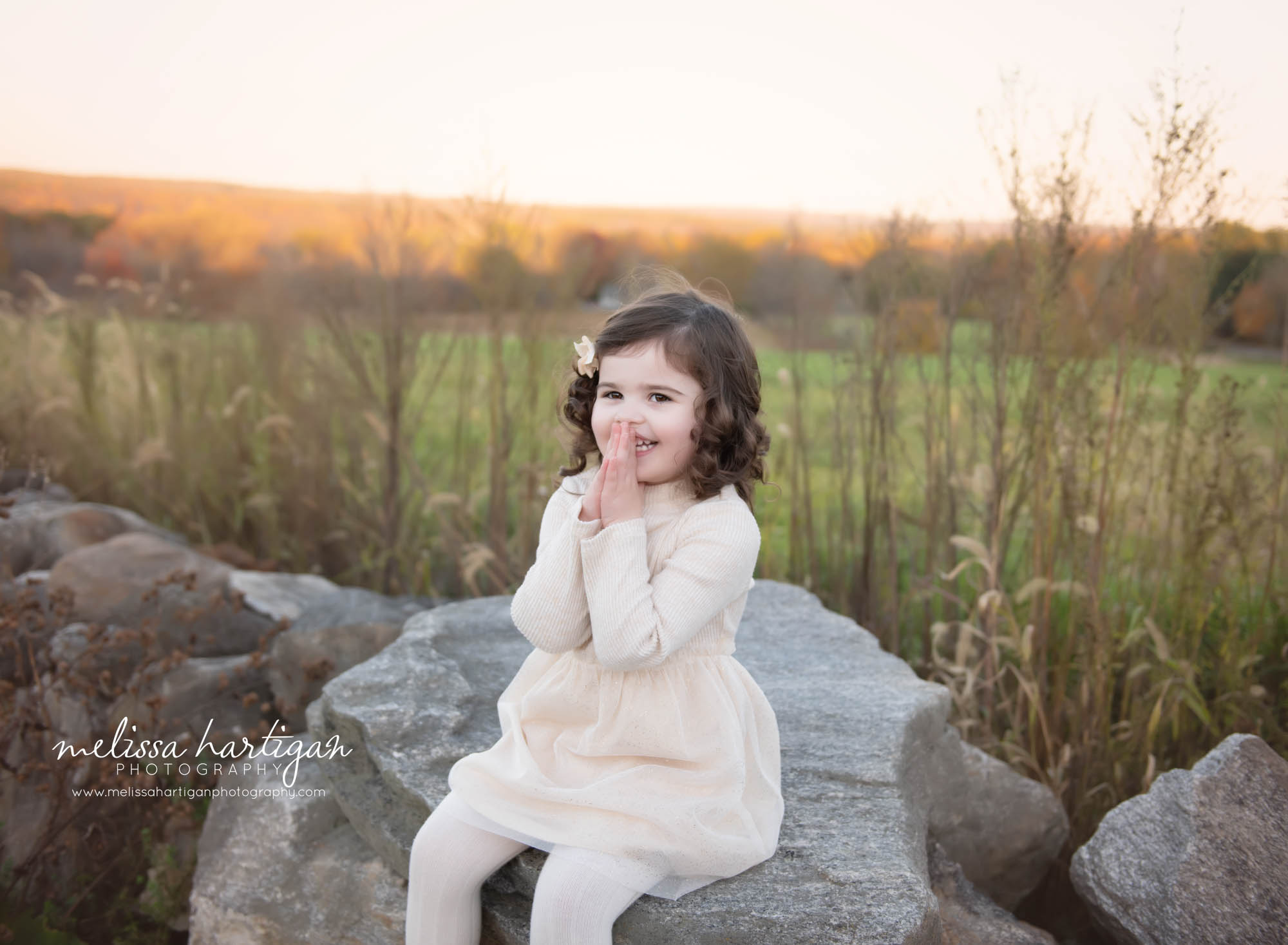 girl sitting on rock holding hands to her face happy smiling CT Family Photography