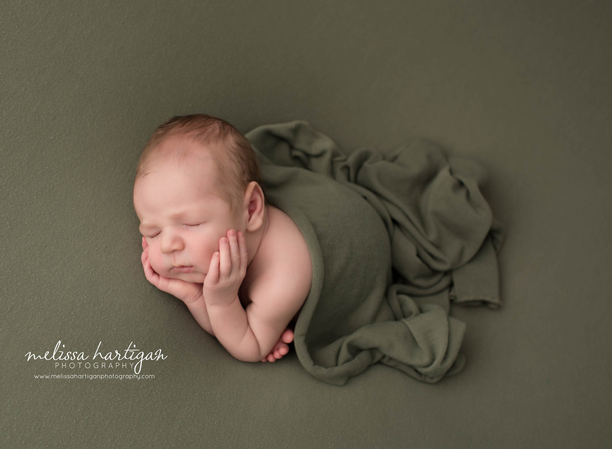 newborn baby boy posed side timber pose with green layer draped over him Newborn Photography Portland CT