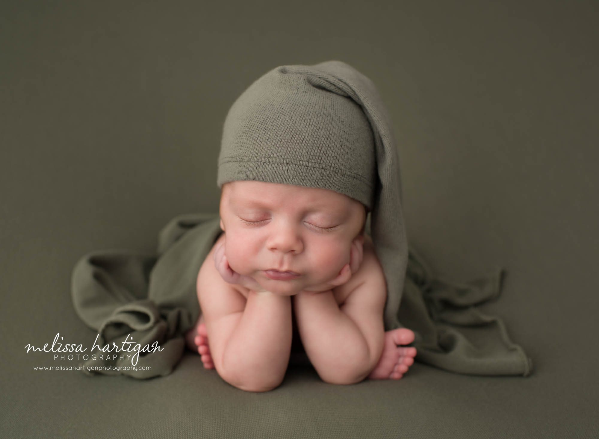 Newborn baby boy posed froggy pose wearing green sleepy cap Willington CT Newborn Photography