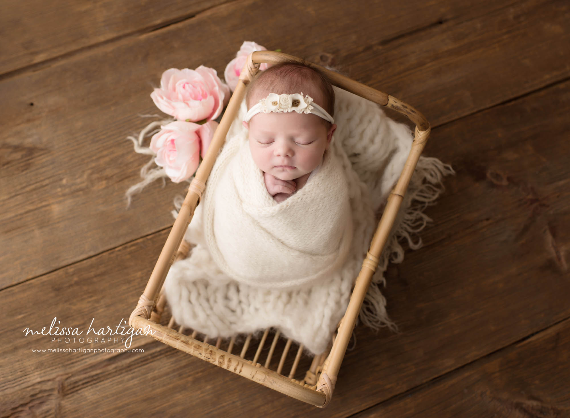 Newborn baby girl swaddle din cream wrap posed in basket with pink flowers Newborn Photography Amston CT