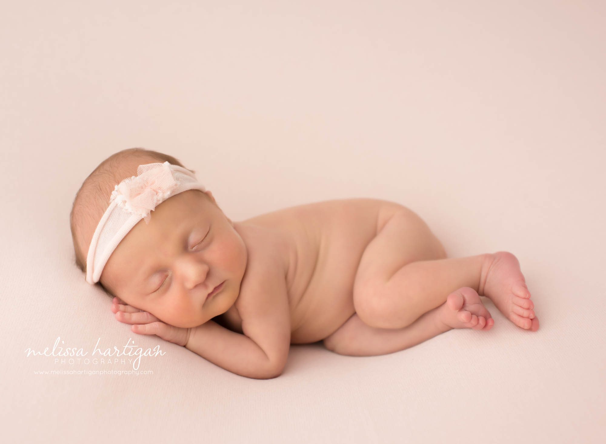 Newborn baby girl posed on side wearing pink headband Newborn Photography Manchester CT