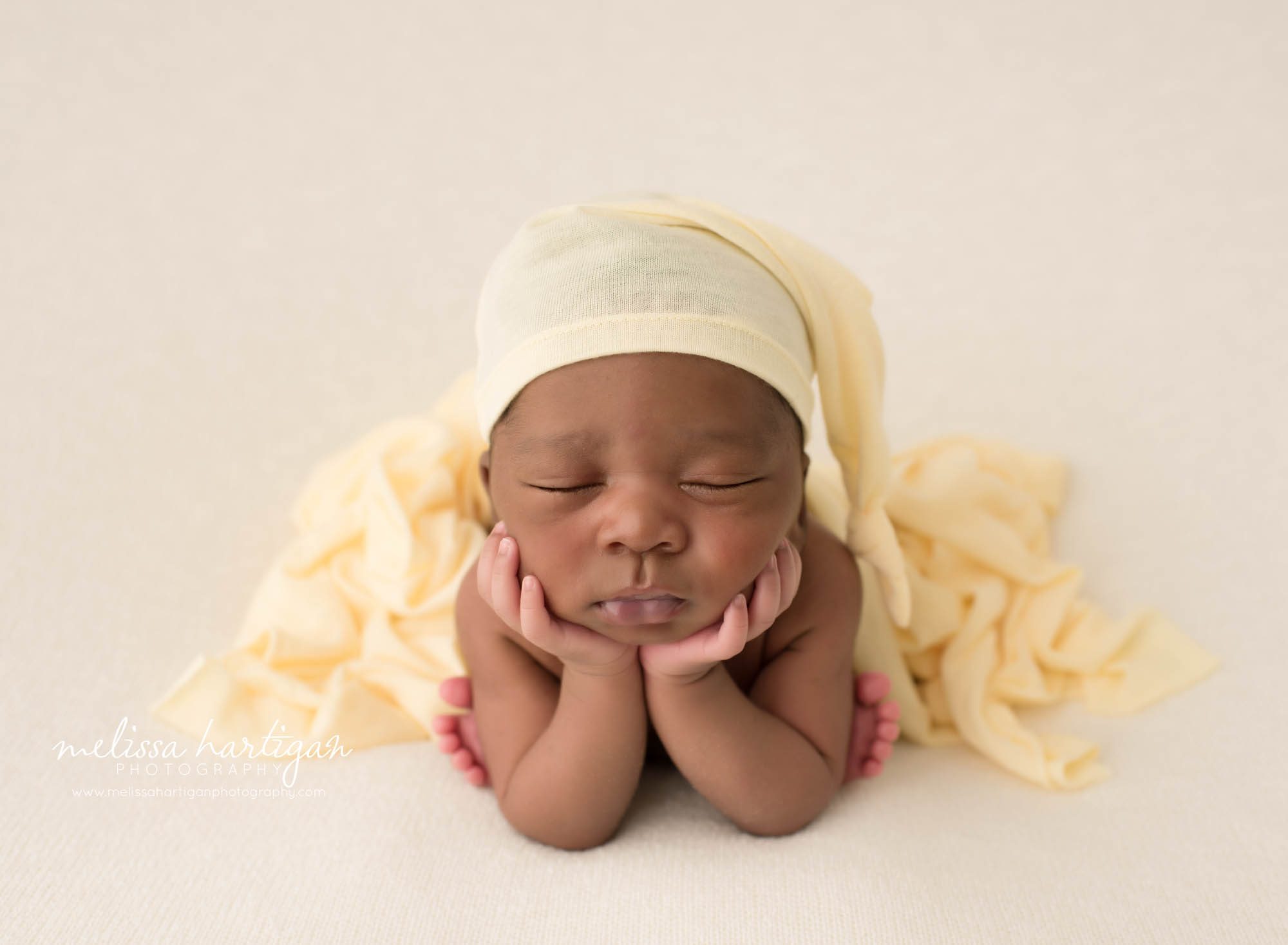 Newborn baby boy posed froggy pose wearing yellow sleepy cap Newborn Photography Durham CT