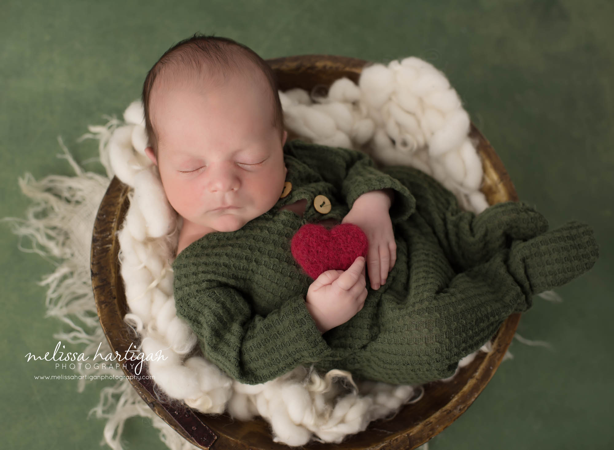 Newborn baby boy posed in wooden bowl wearing green waffle knit outfit