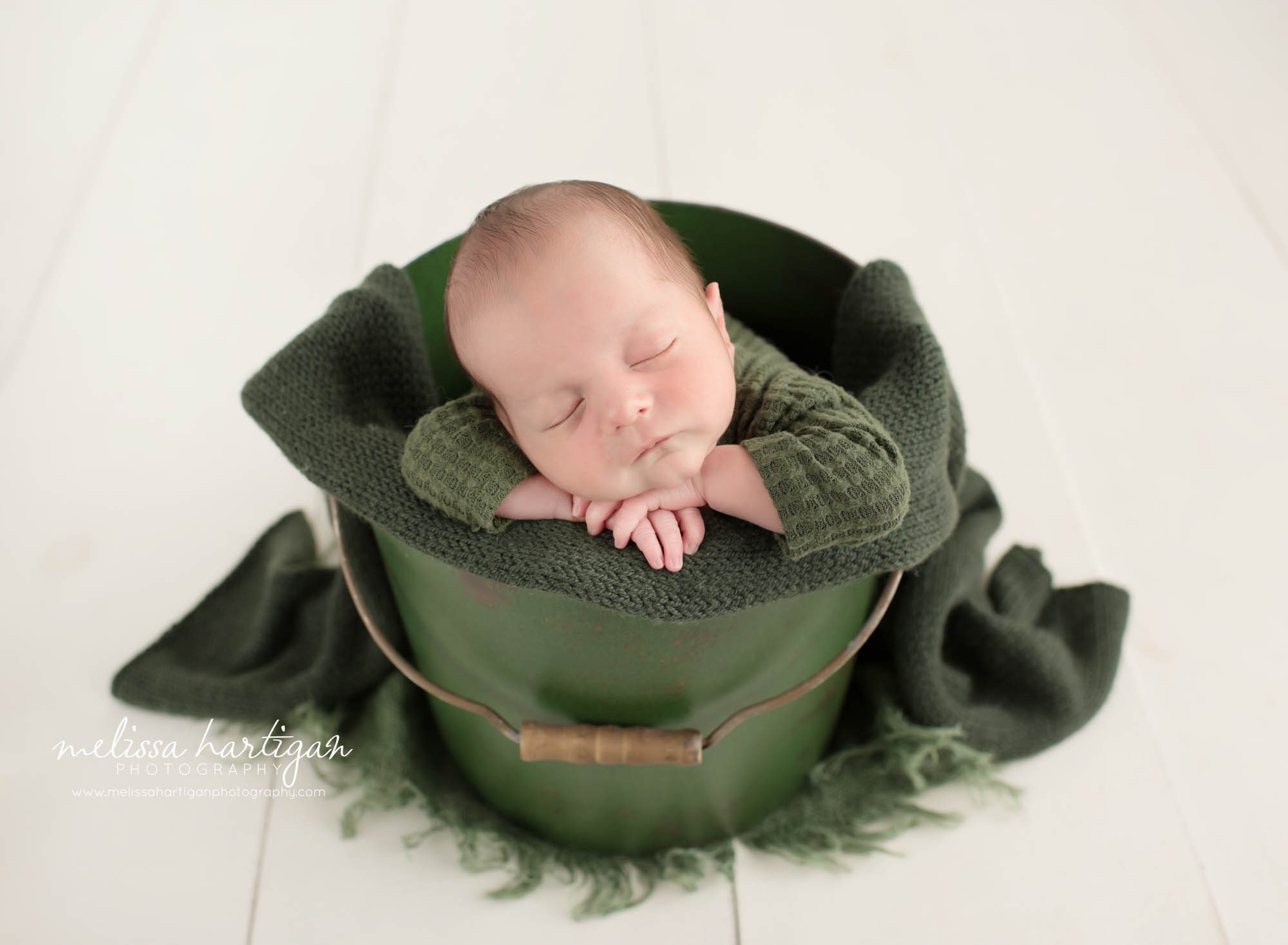Newborn baby boy posed in green bucket
