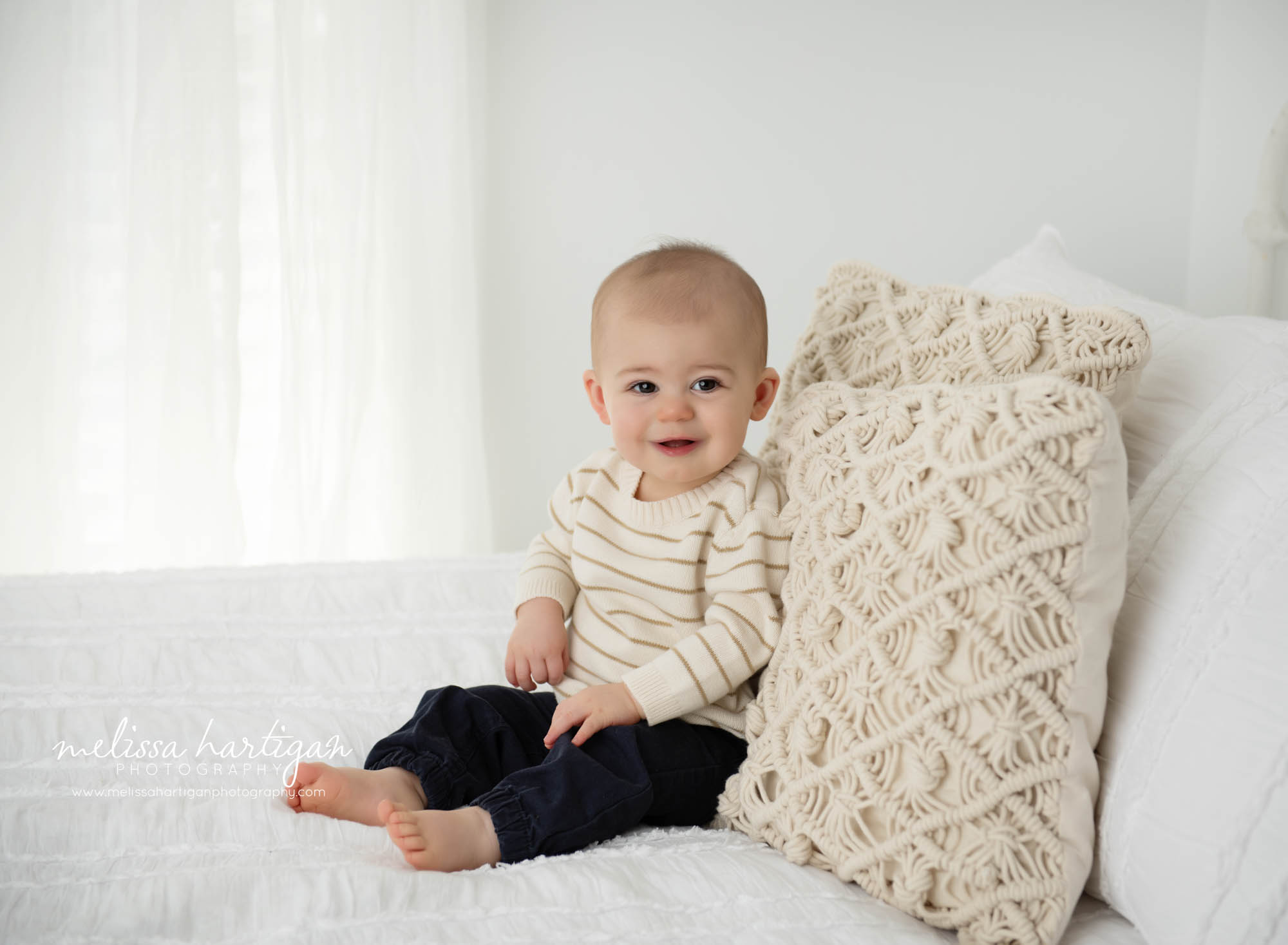 Baby boy sitting on bed happy smiling in photography studio