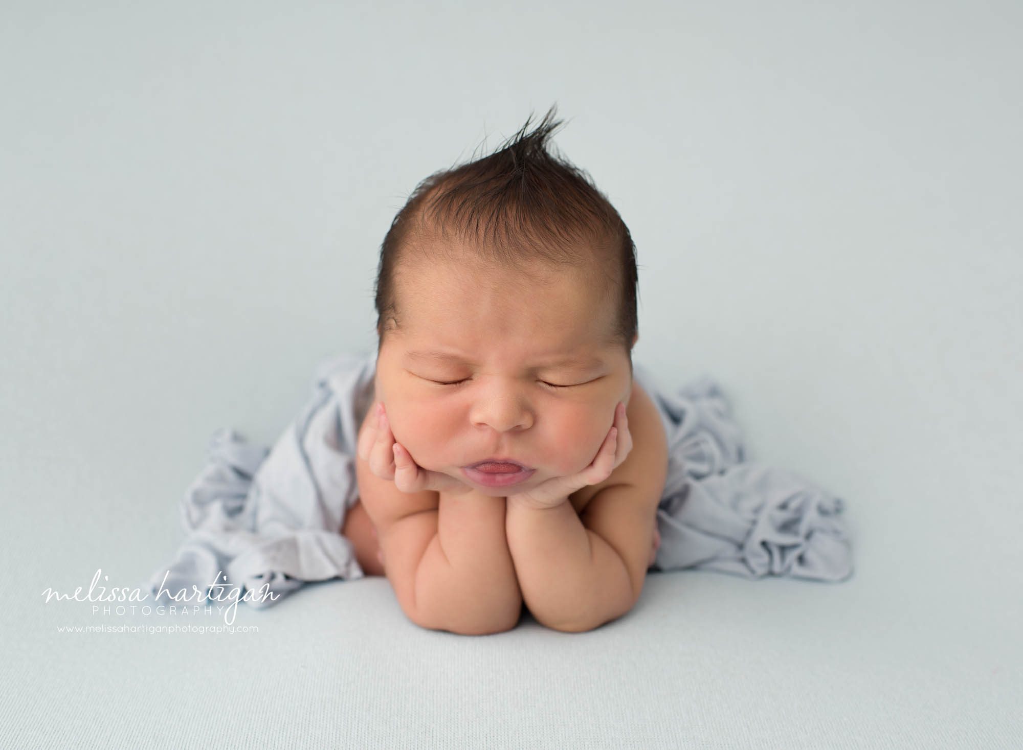 Newborn baby boy posed on blue backdrop in froggy pose Newborn Photography Norwich CT