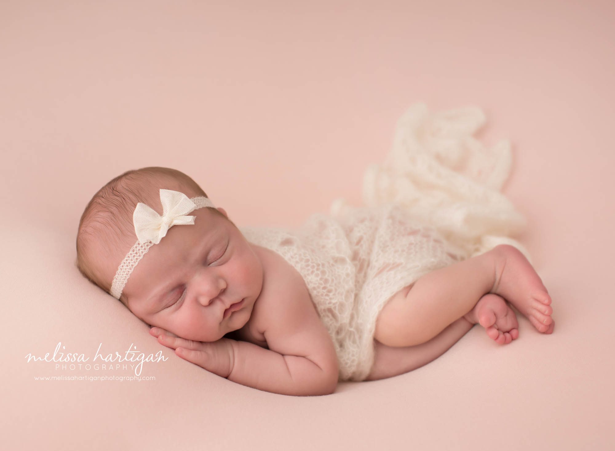Newborn baby girl posed on side with knitted draped layer wearing bow headband Newborn Photography Ivoryton CT