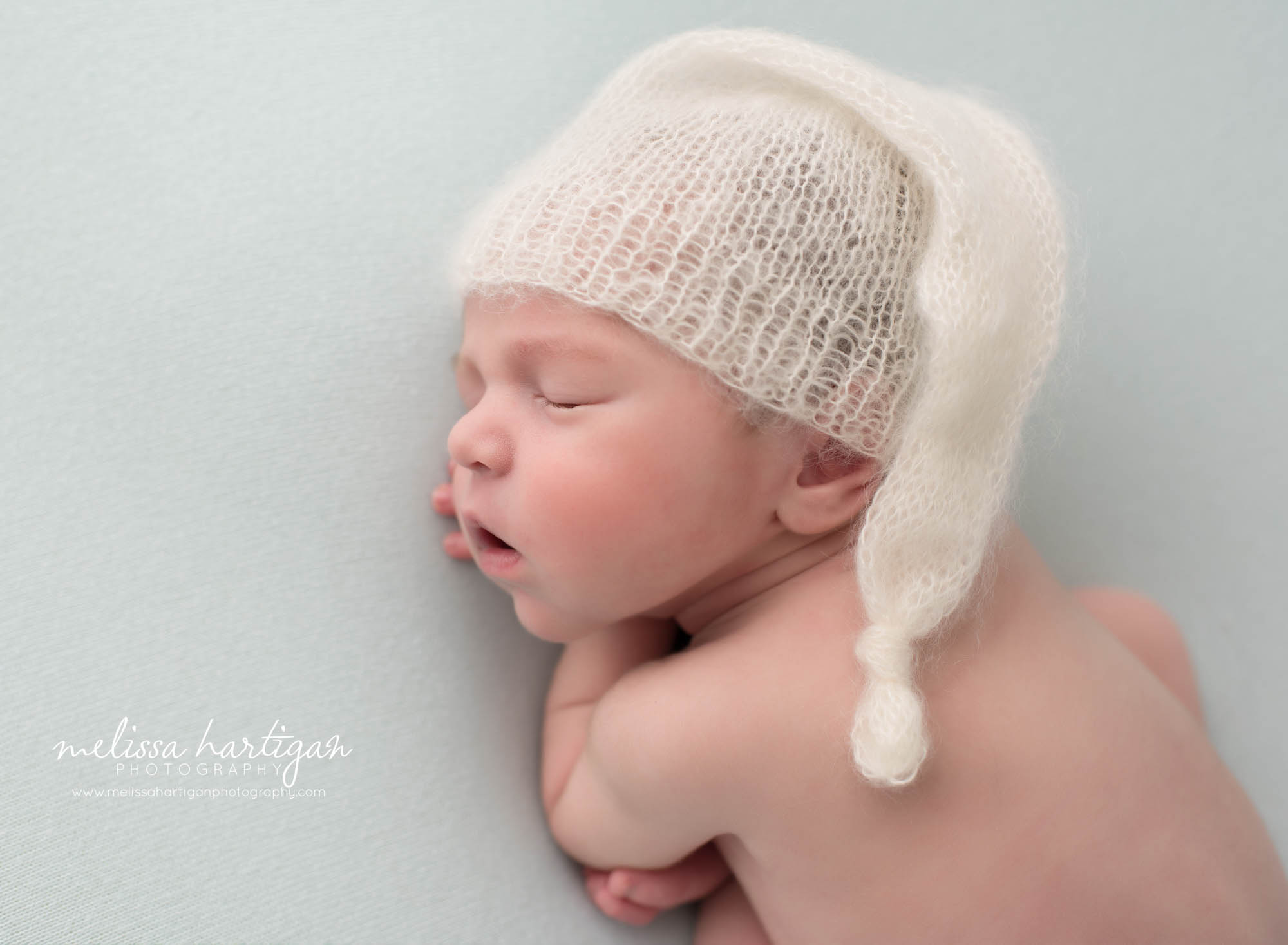 Newborn baby boy posed sleeping wearing knitted cream sleepy cap