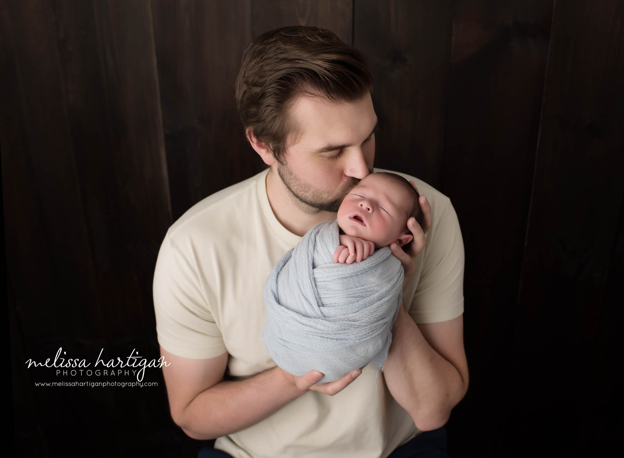 Dad kissing newborn son on head in parents pose Newborn Photography Hebron CT