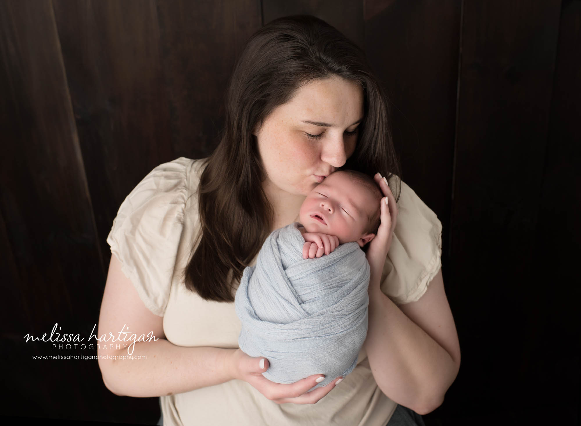 mom kissing son on forehead in parents pose newborn photoshoot