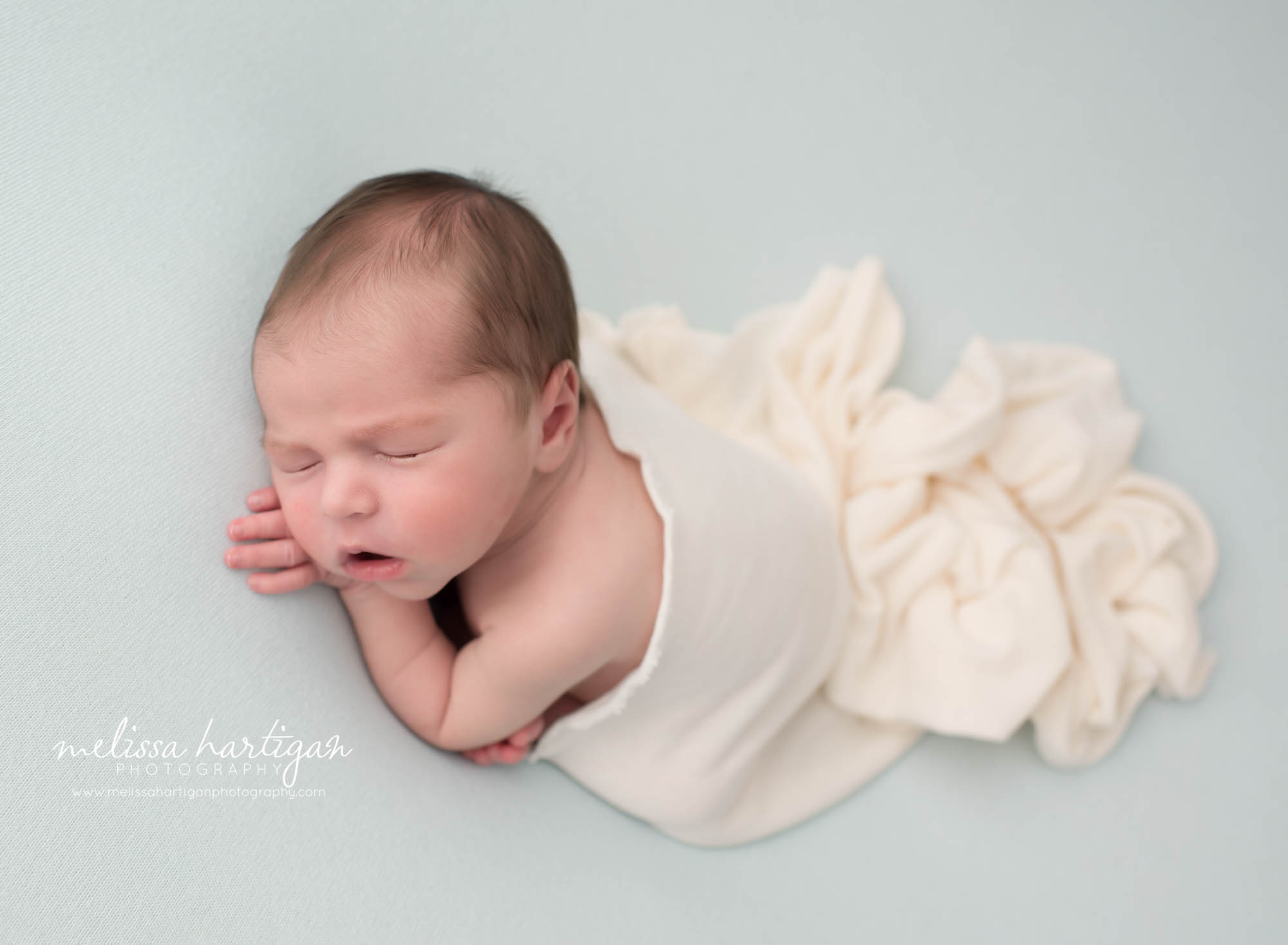 Newborn baby boy posed on tummy with cream layer draped over back Newborn Photography Hebron CT