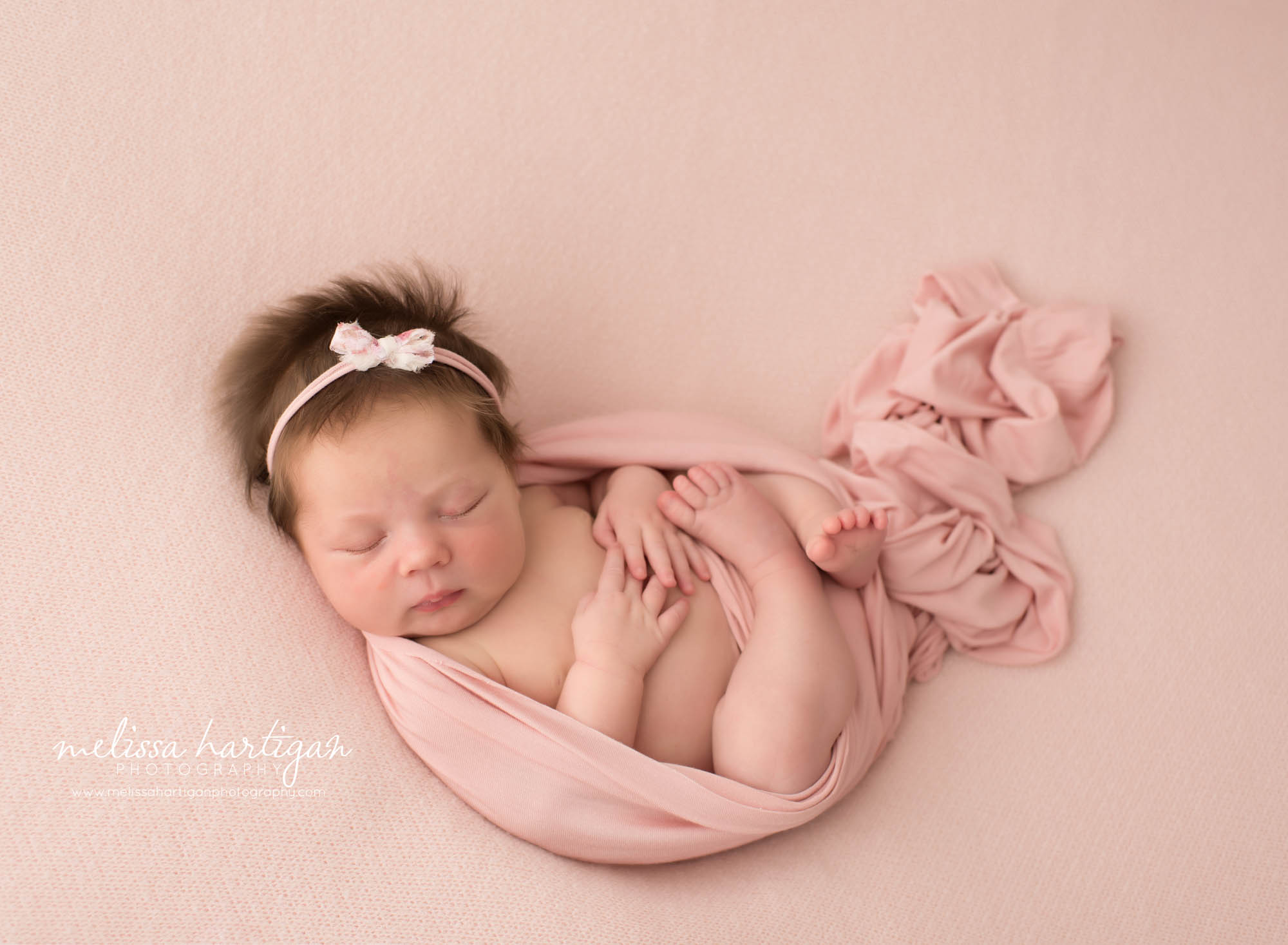 Newborn baby girl posed on back with pink wrap draped around her Hebron CT Newborn Photography