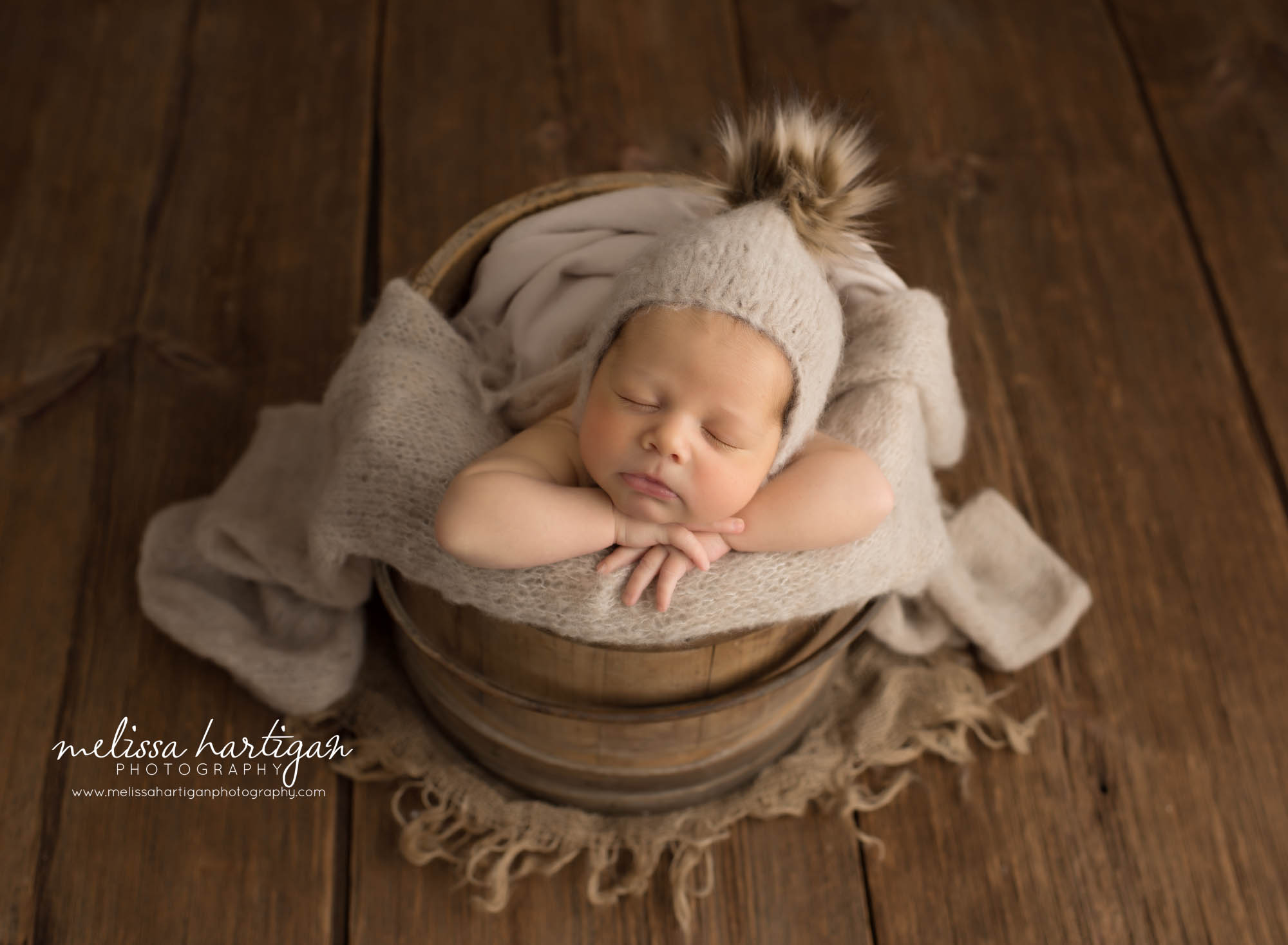 newborn baby boy posed in bucket wearing beige pom bonnet Hebron CT Newborn Photography