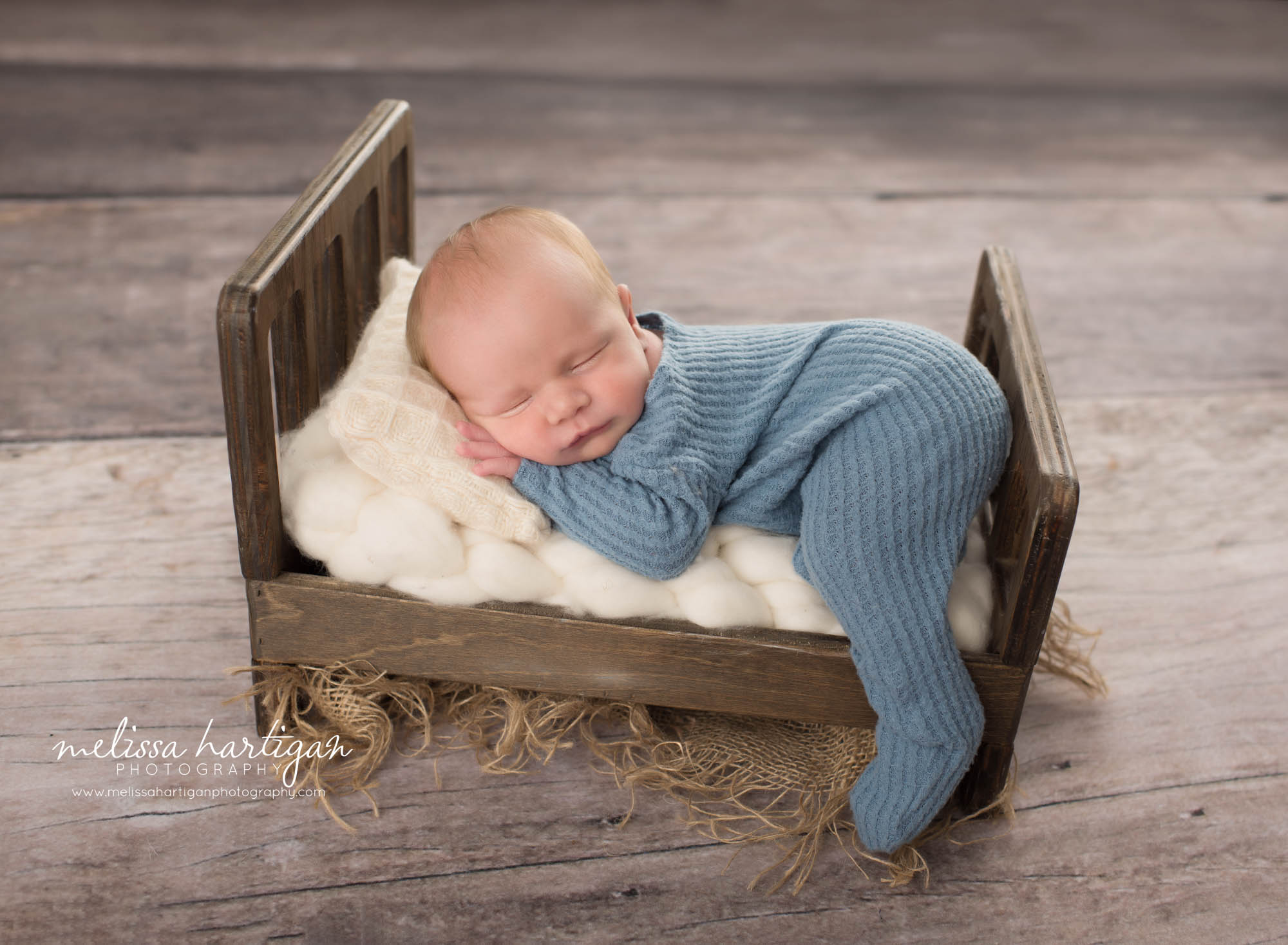 Newborn baby boy posed on wooden bed Newborn Photography Charlton MA