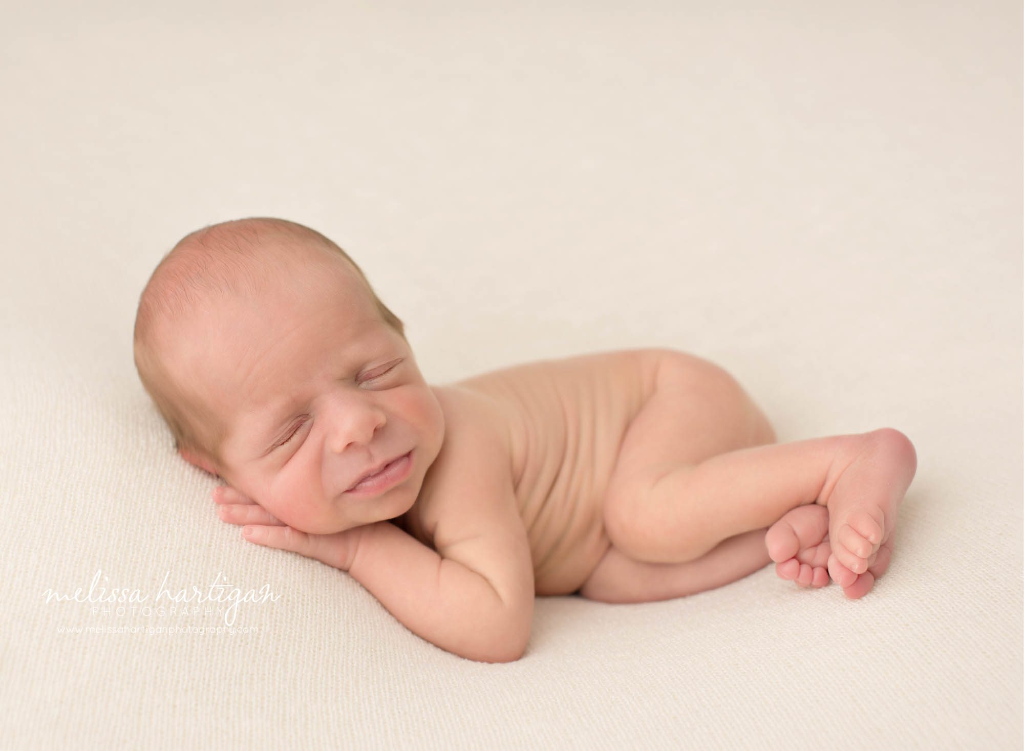 Newborn baby boy posed on side sleeping