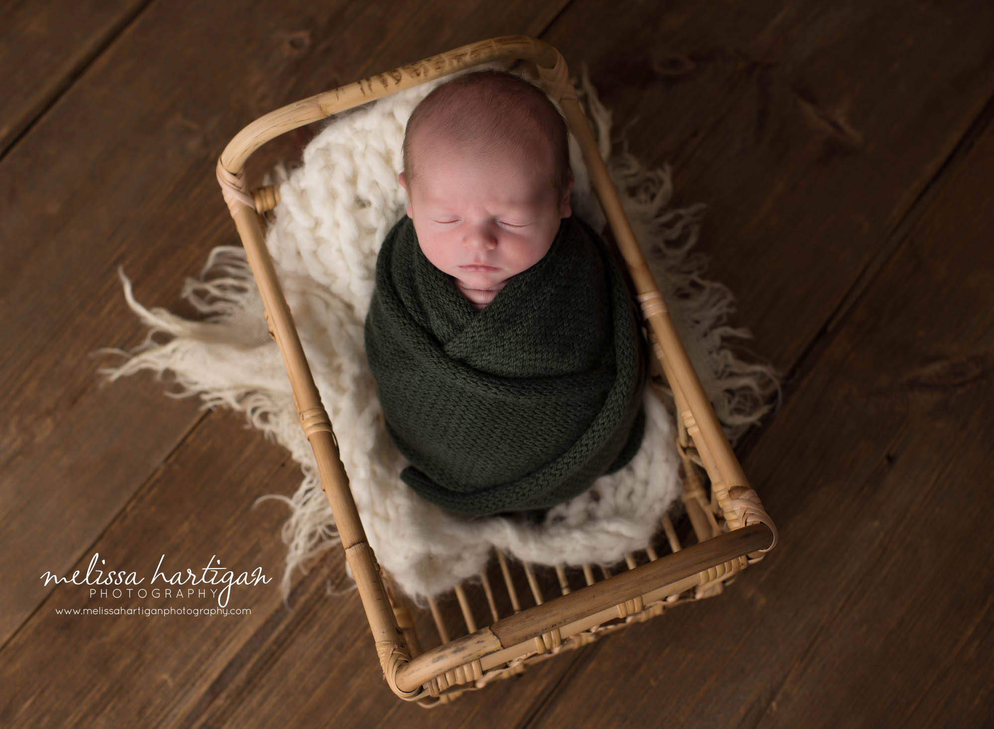 Newborn baby boy swaddled in green knit wrap posed in basket Newborn Photography Vernon CT