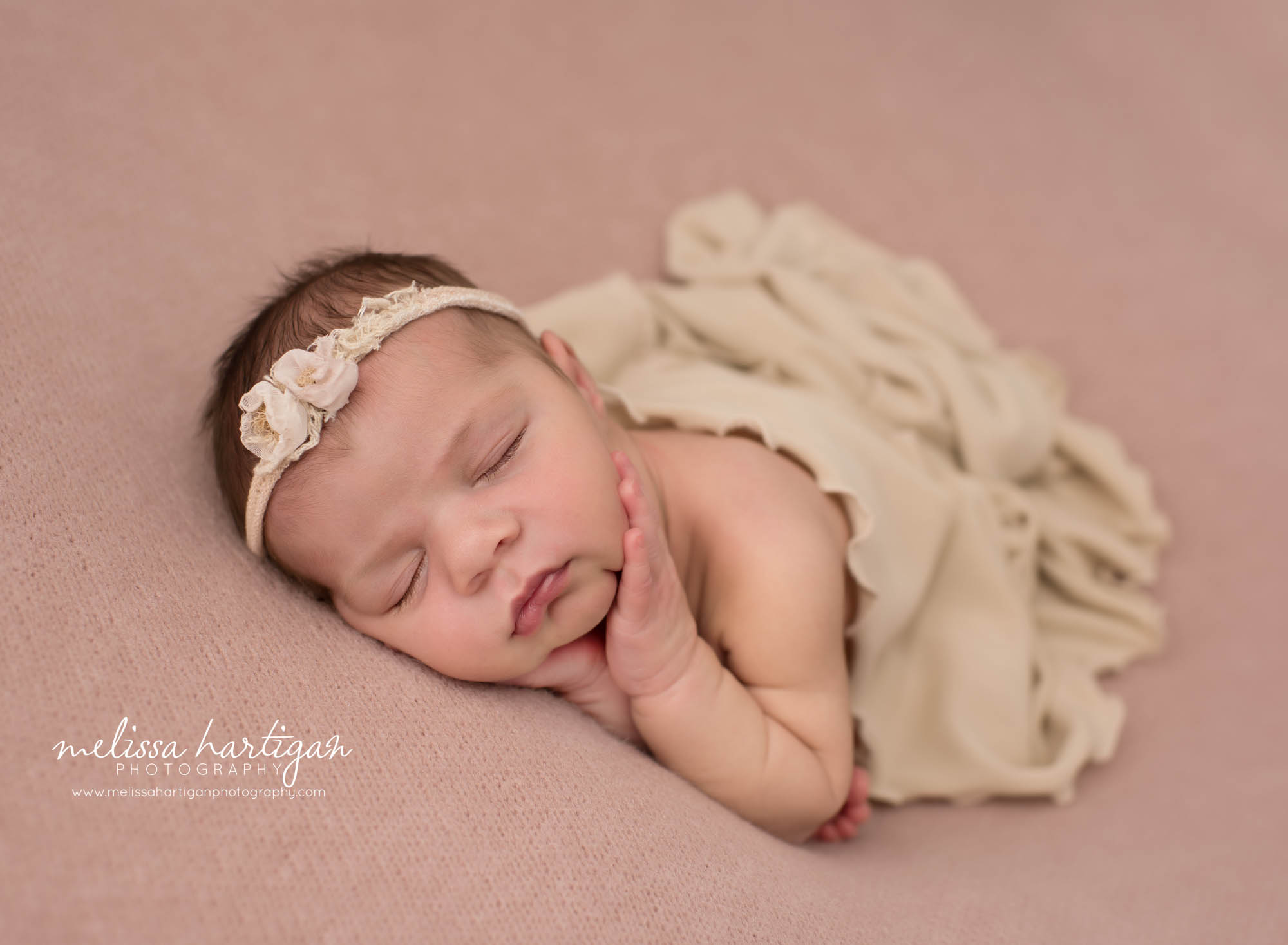 Newborn baby girl posed on pink backdrop wearing cream flower headband Newborn Photography Norwich CT