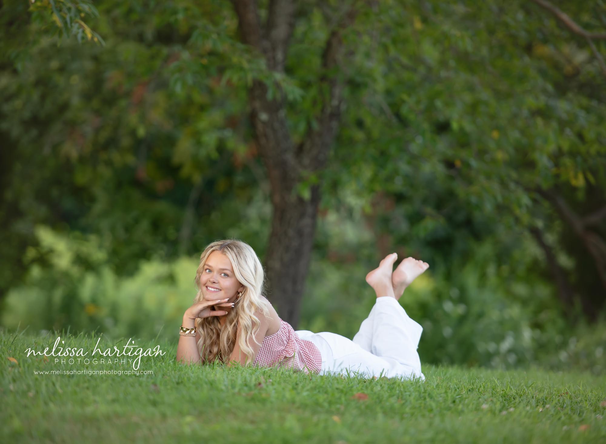 Girl laying in grass smiling at camera high school senior portrait