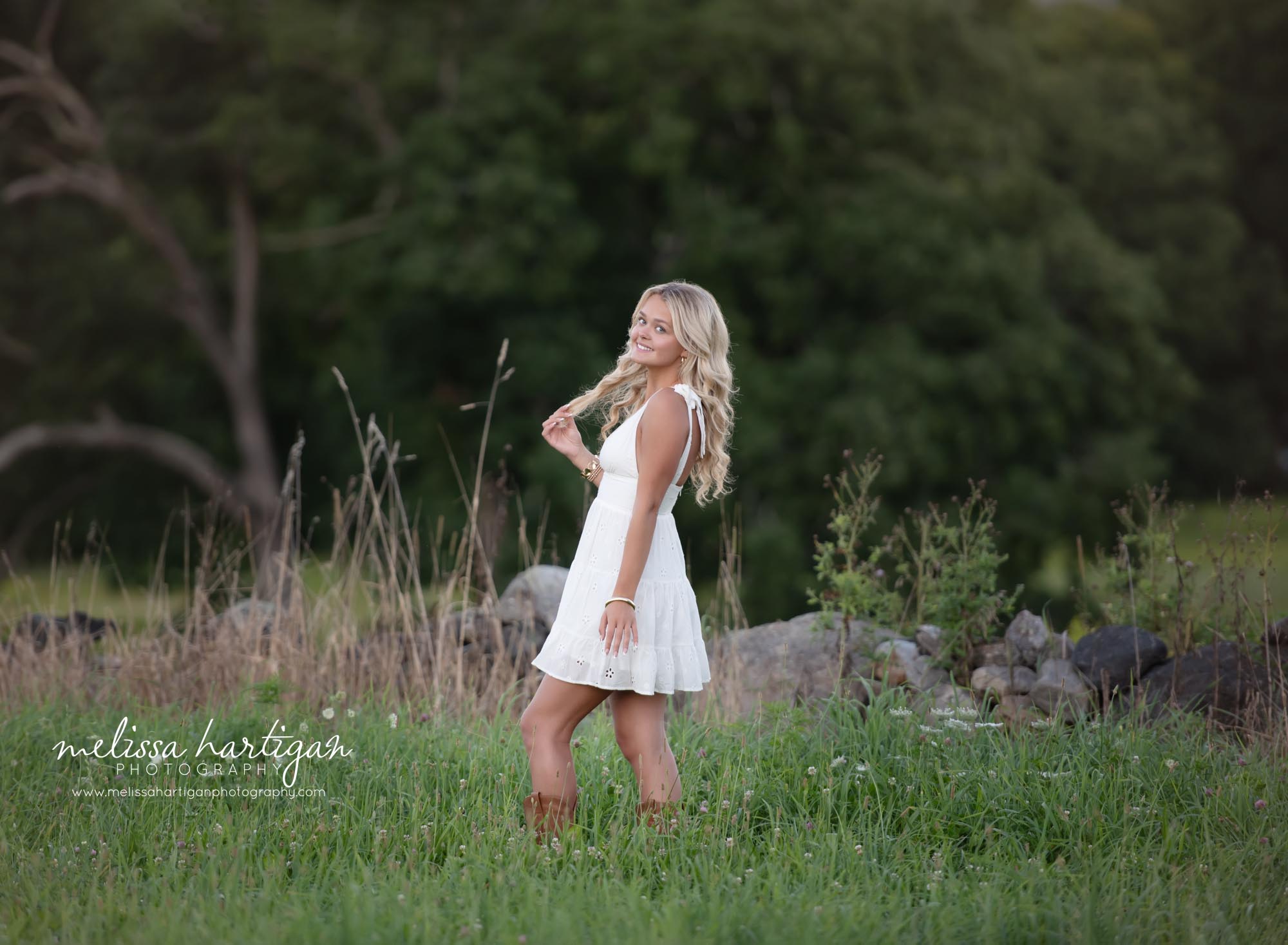 girl standing in grassy field smiling holding her hair Coventry CT Senior Photography