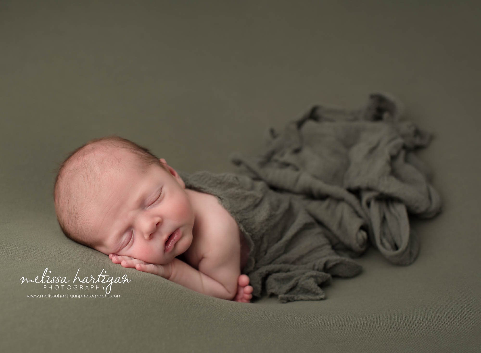 Newborn baby boy posed modified taco pose with green layer draped over him Newborn Photography Vernon CT