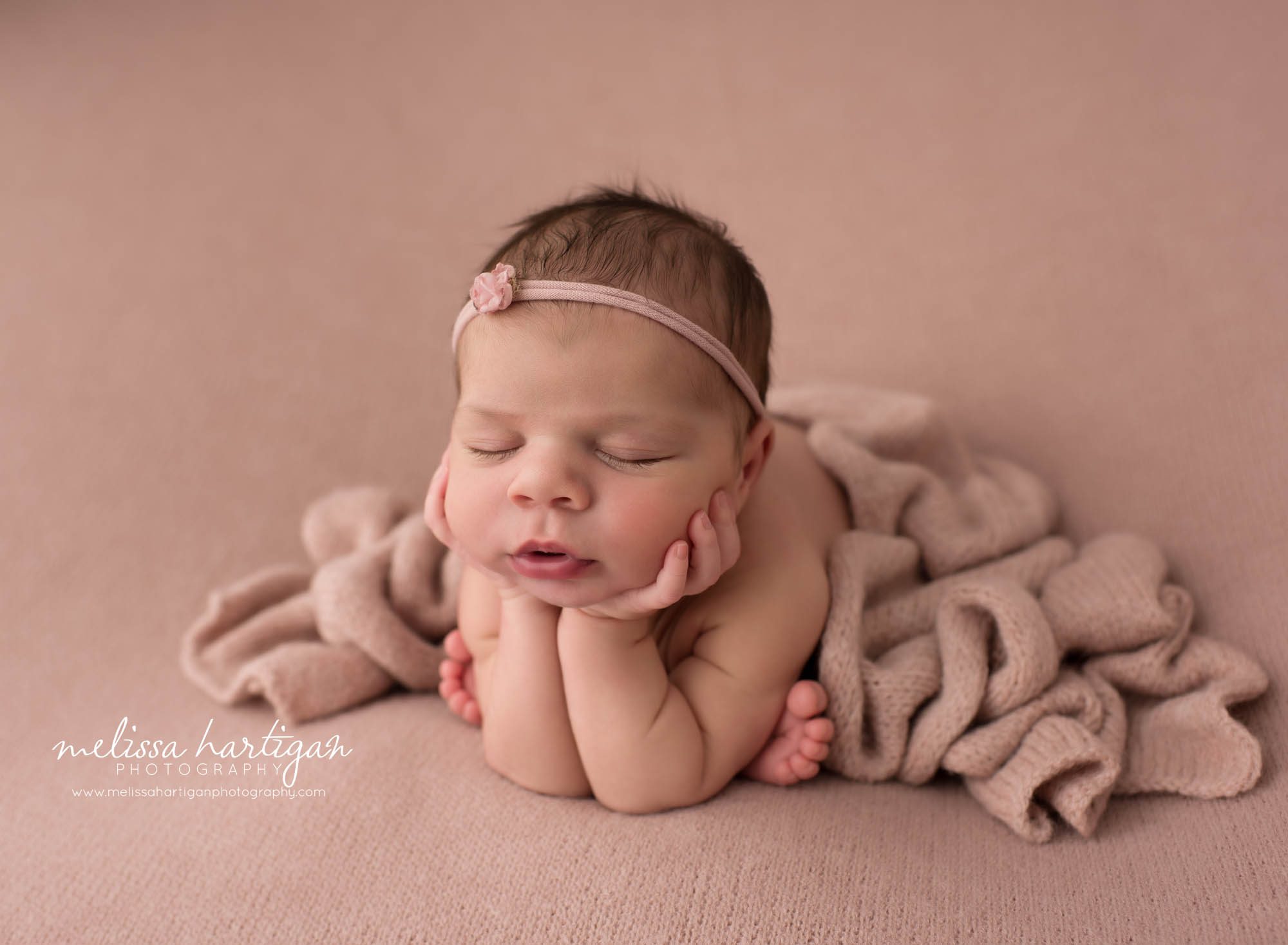 Newborn baby girl posed froggy pose with pink layer draped over Newborn Photography Norwich CT