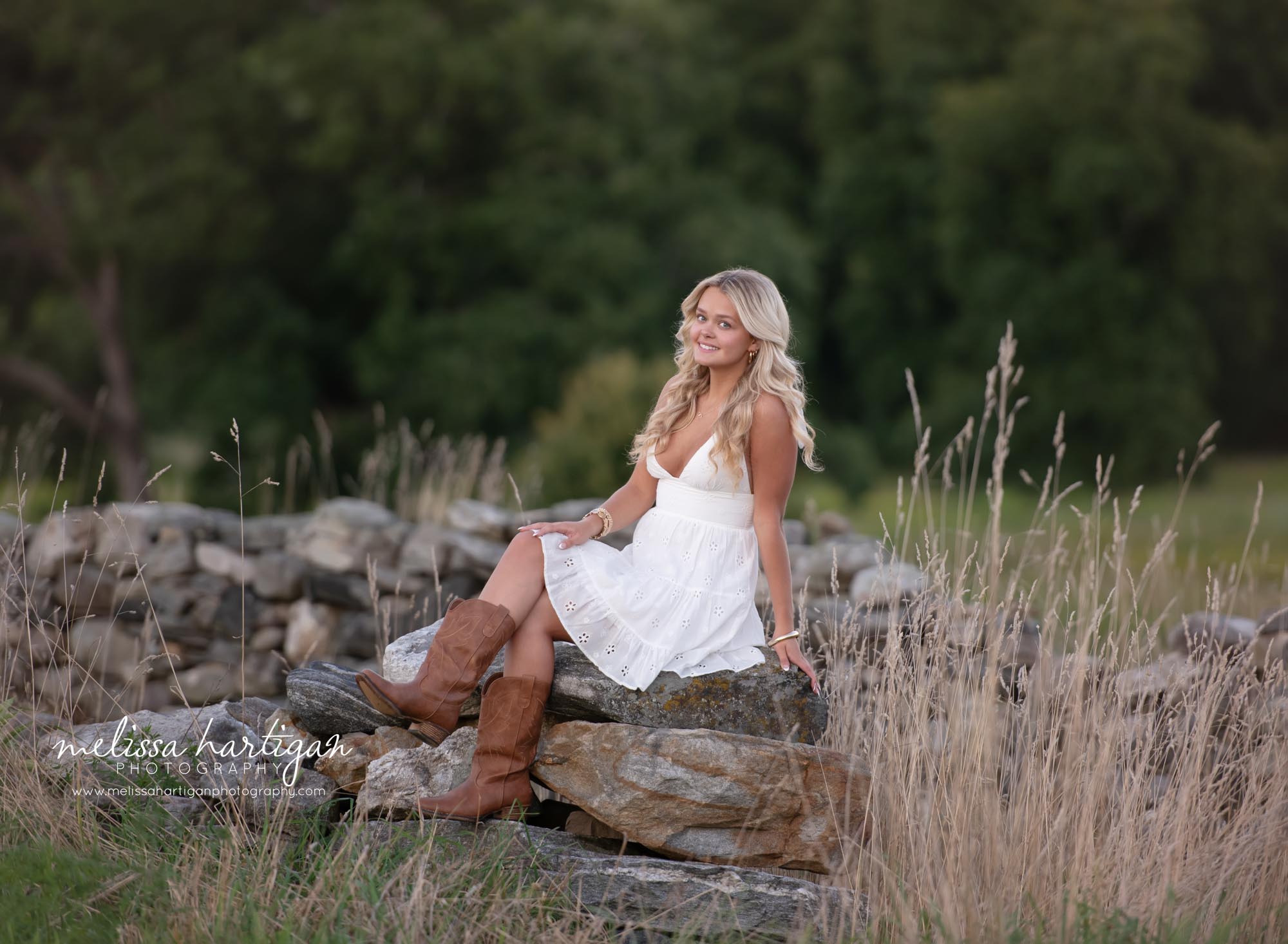 Girl sitting on rocks with hand on knee pose happy smiling high school senior photoshoot Coventry CT Senior Photography
