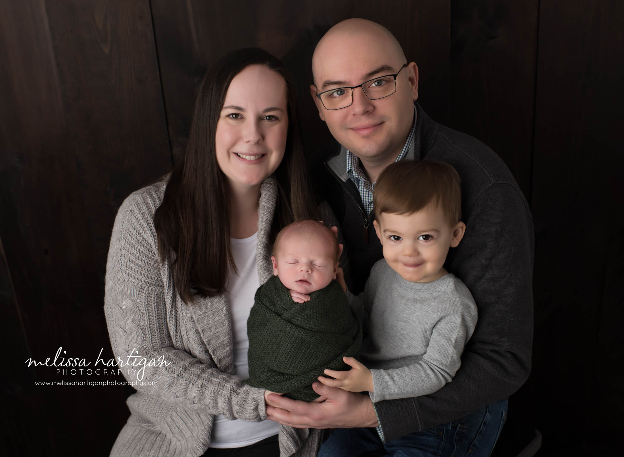 Mom dad and big brother posed together with newborn baby boy for family pose Newborn Photography Vernon CT