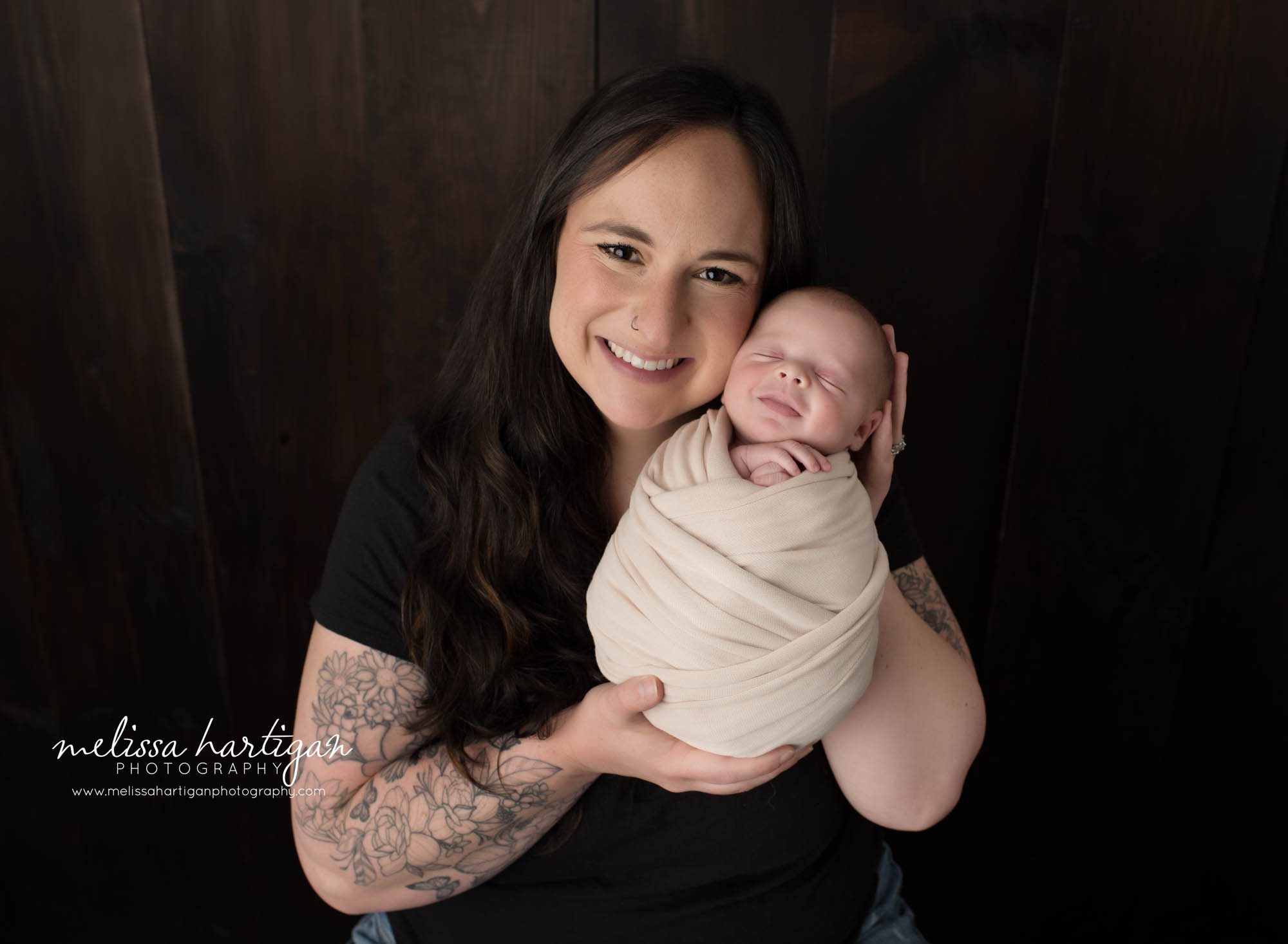 Mom holding newborn son in parents pose baby boy smiling